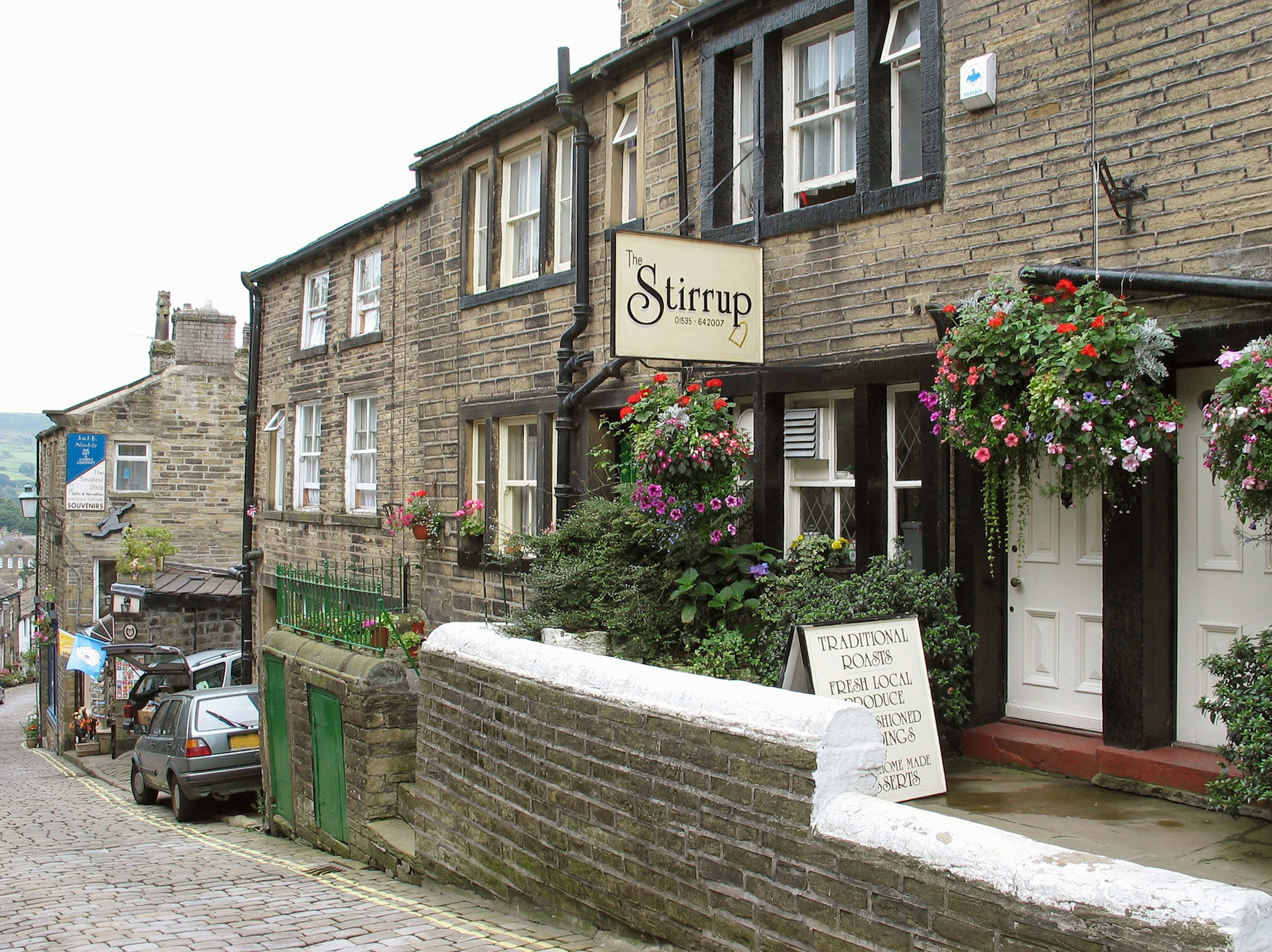 Stirrup Pub mit Steingebäuden und lebhaften Blumen entlang einer Kopfsteinpflasterstraße