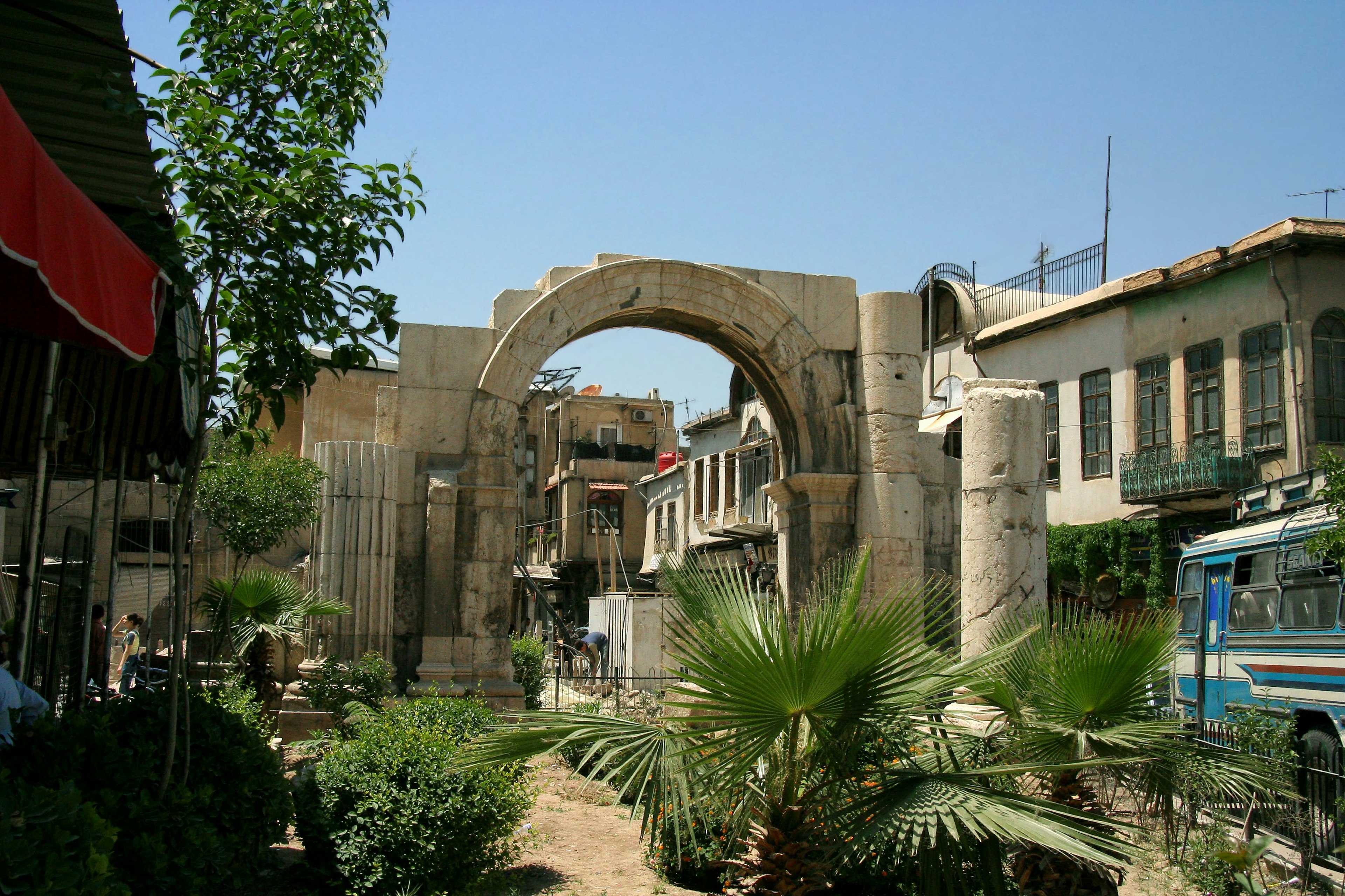 Arco antico con edifici moderni e vegetazione