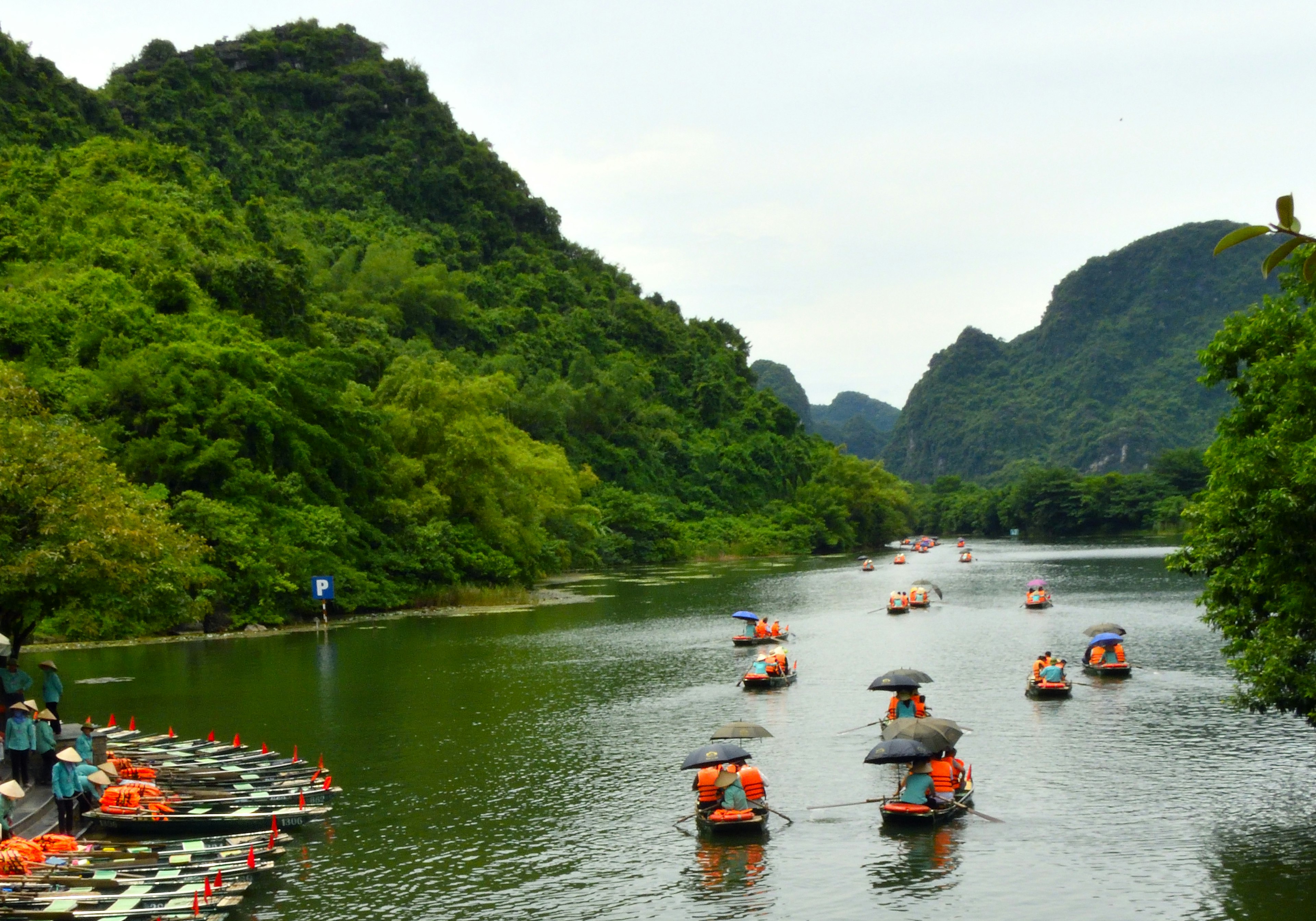 风景如画的河流，四周环绕着郁郁葱葱的山脉和旅游船