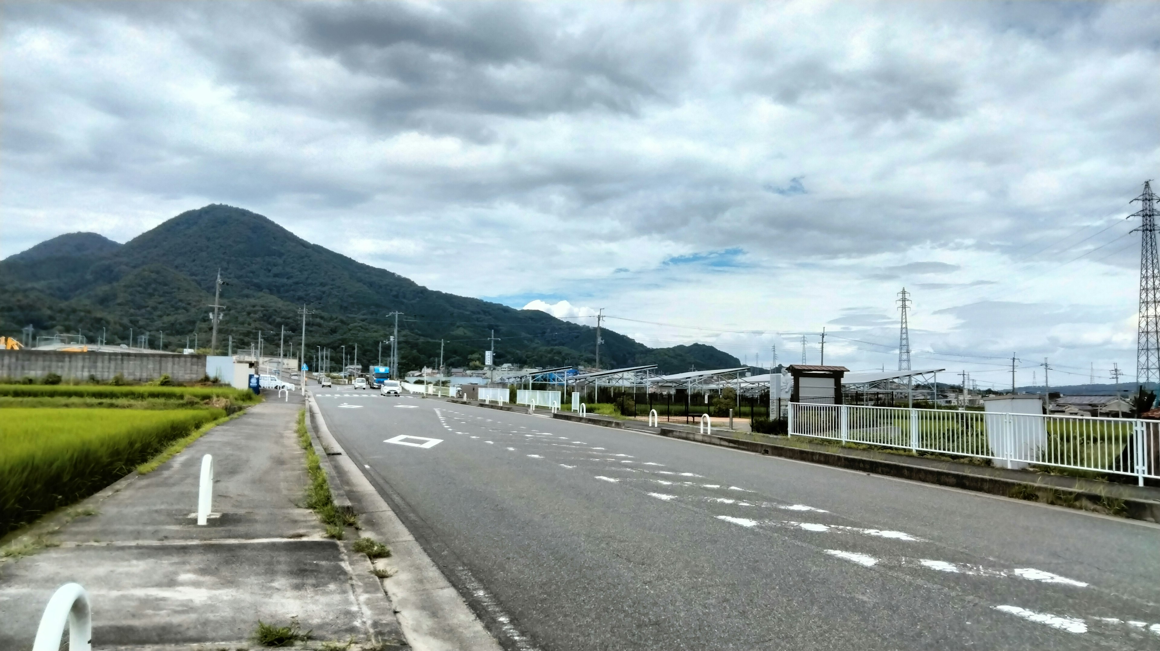 Escena de carretera tranquila con campos de arroz y montañas al fondo