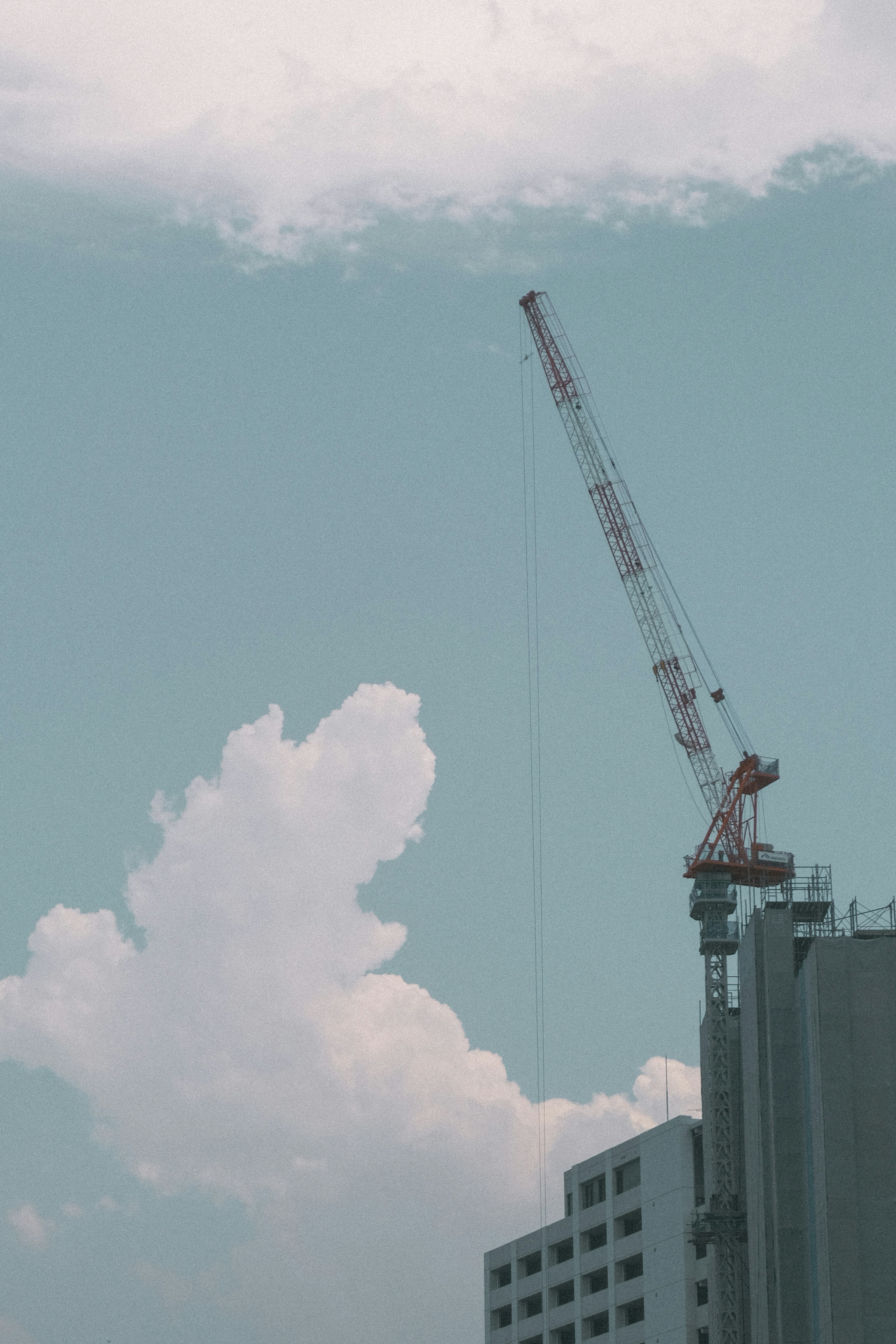 Kran, der sich gegen einen blauen Himmel mit Wolken erhebt