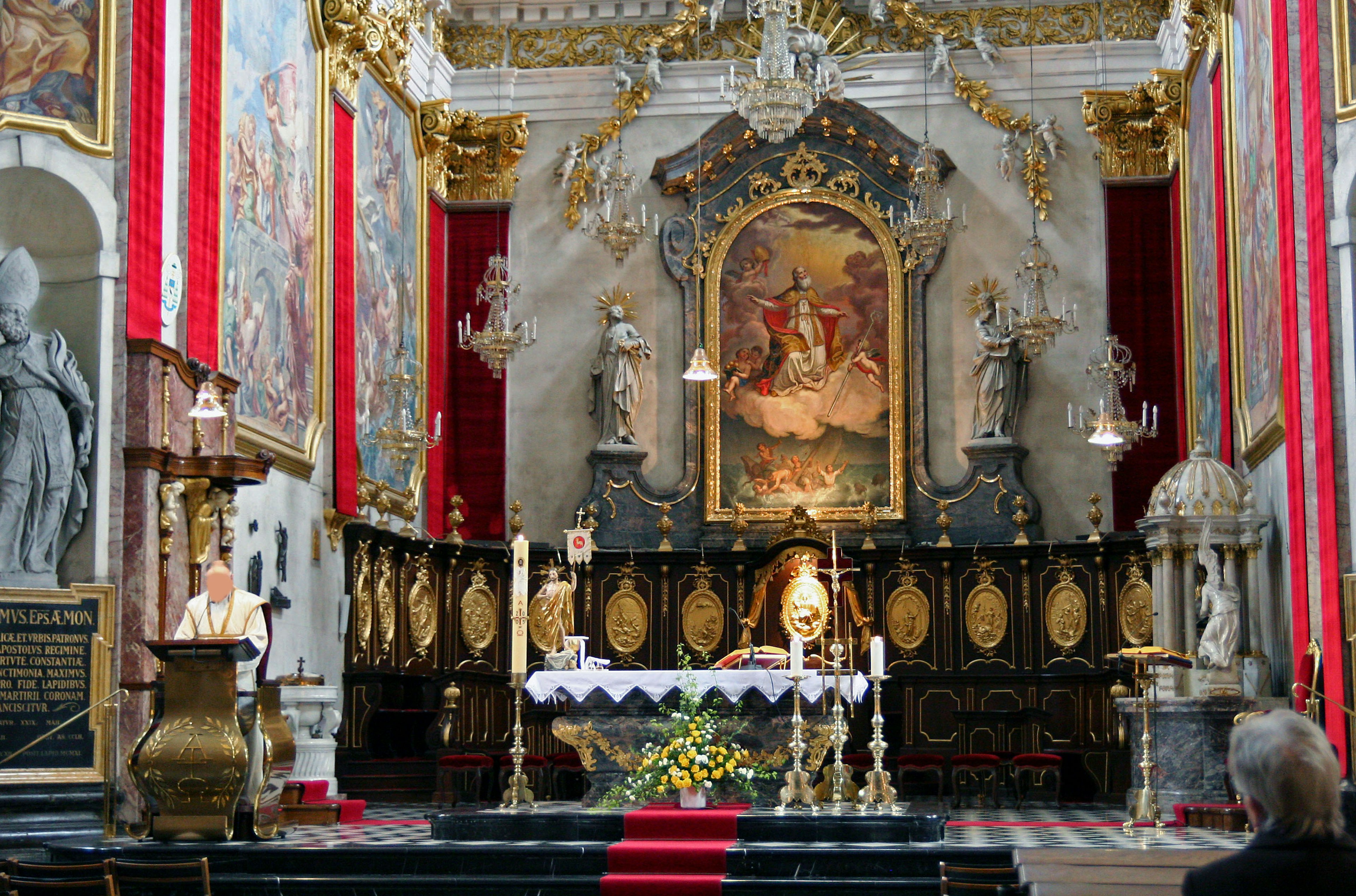 Innenraum einer Kirche mit einem Altar religiösem Gemälde Skulpturen und roten Vorhängen