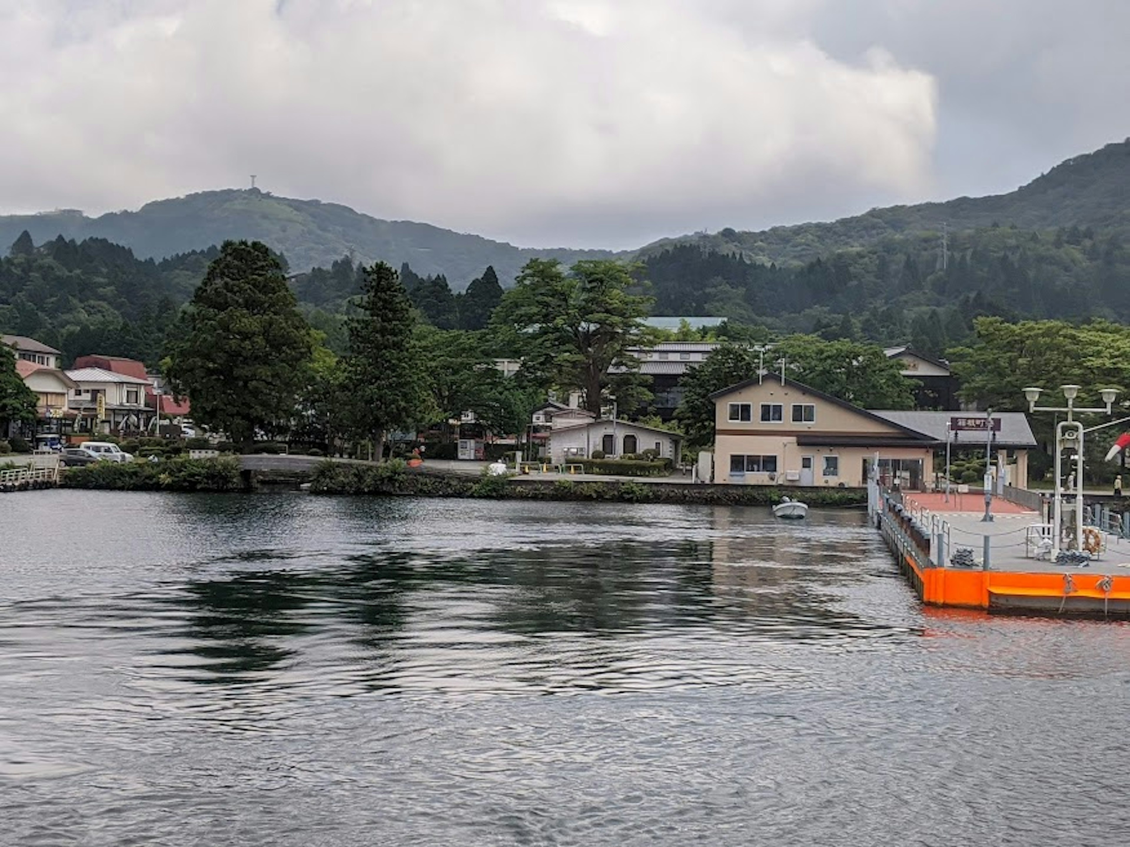 Vue pittoresque d'une ville au bord d'un lac avec des montagnes verdoyantes et un ciel nuageux