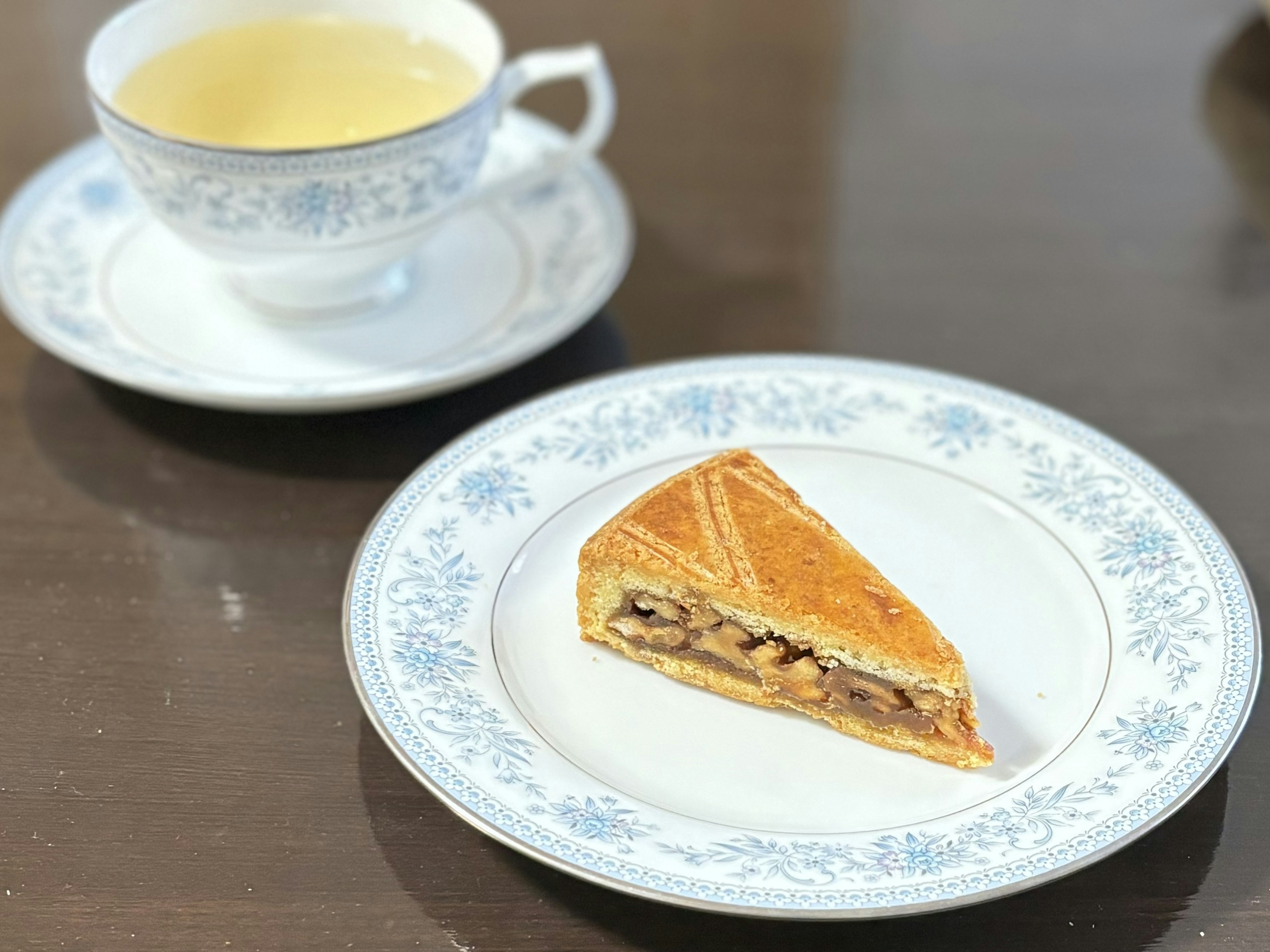 Un plato bien presentado con una rebanada de pastel y una taza de té