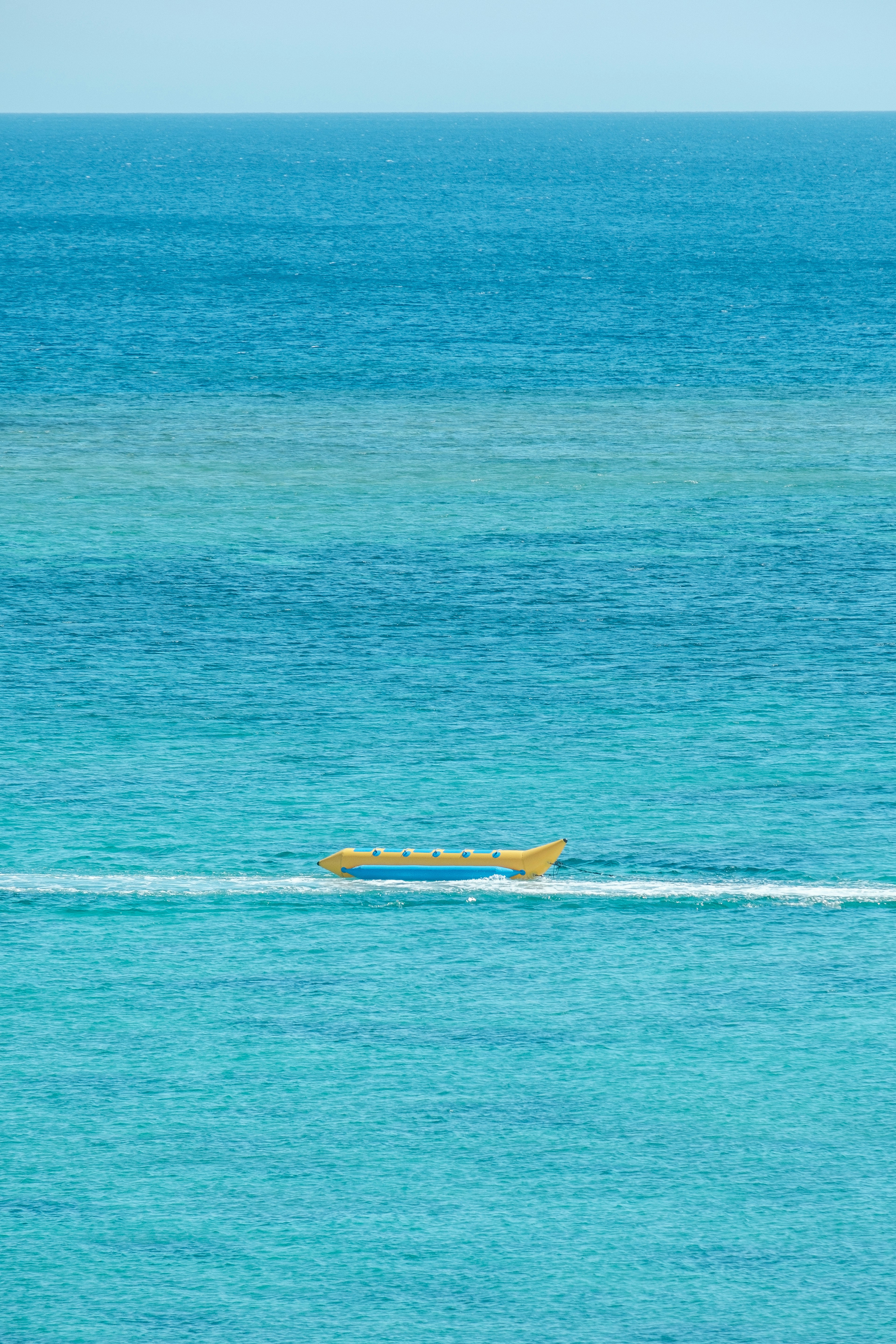 Barca gialla che scivola su un oceano blu