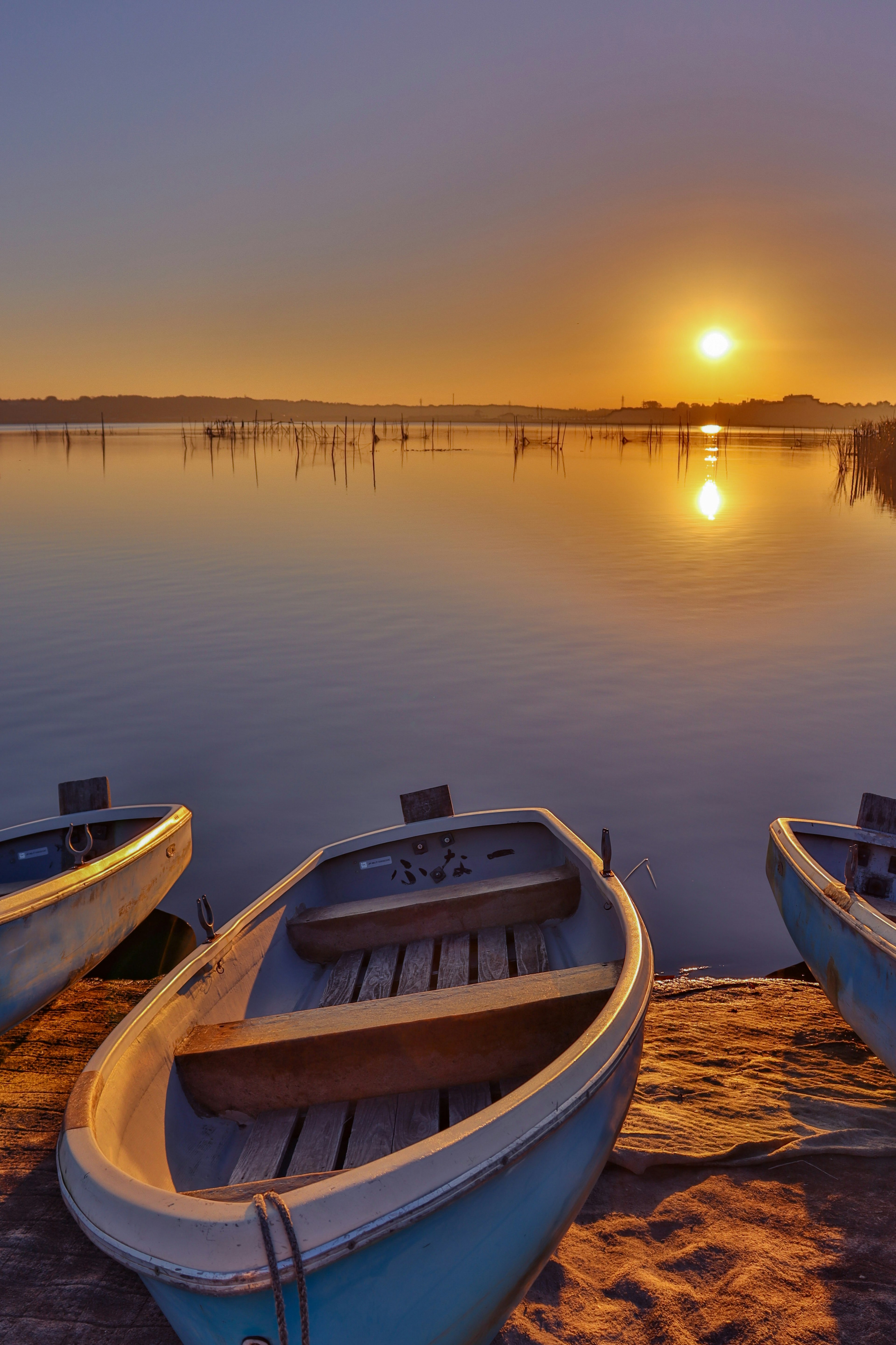 Botes en un lago tranquilo al atardecer con reflejos