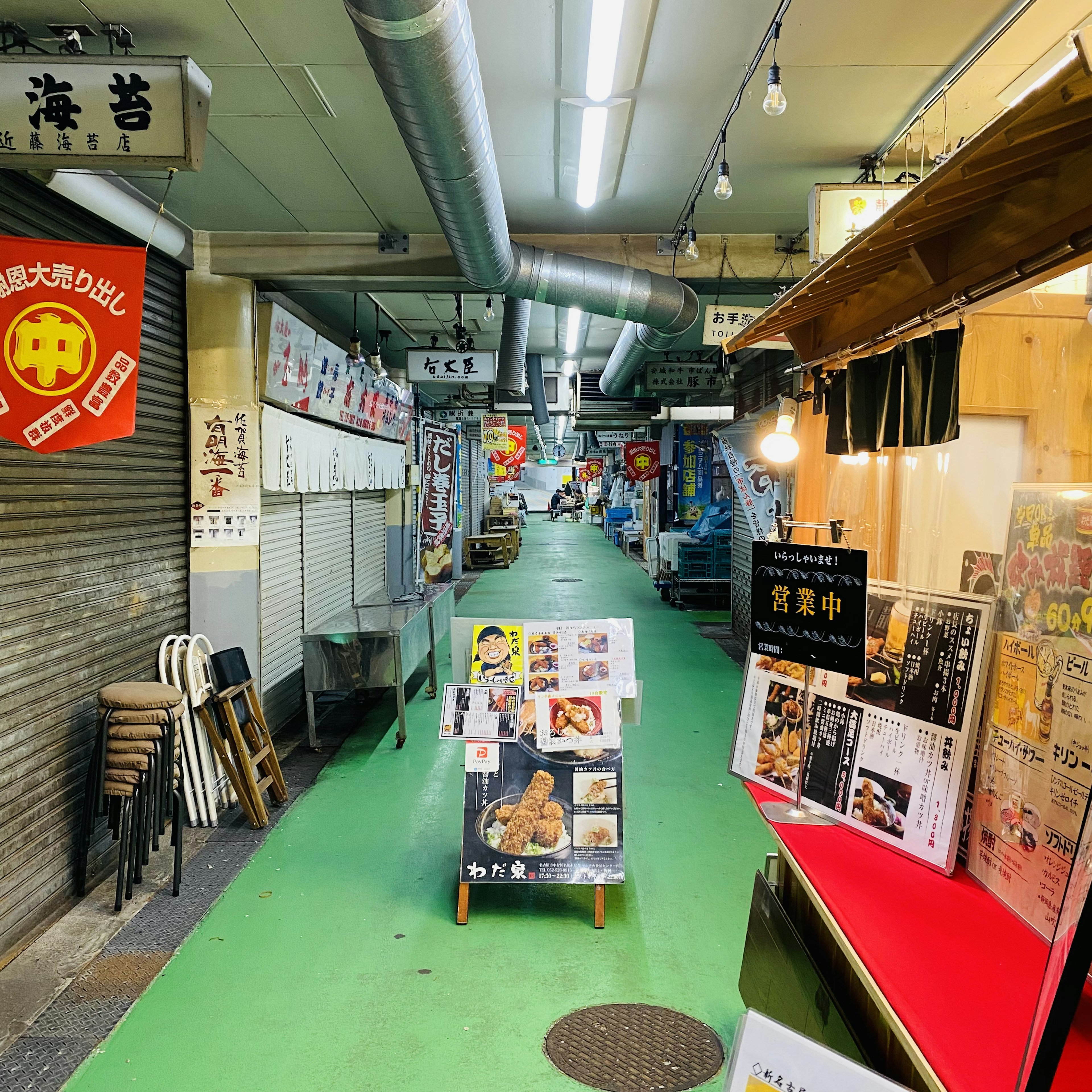 Callejón estrecho flanqueado por letreros de restaurantes y asientos en una calle comercial