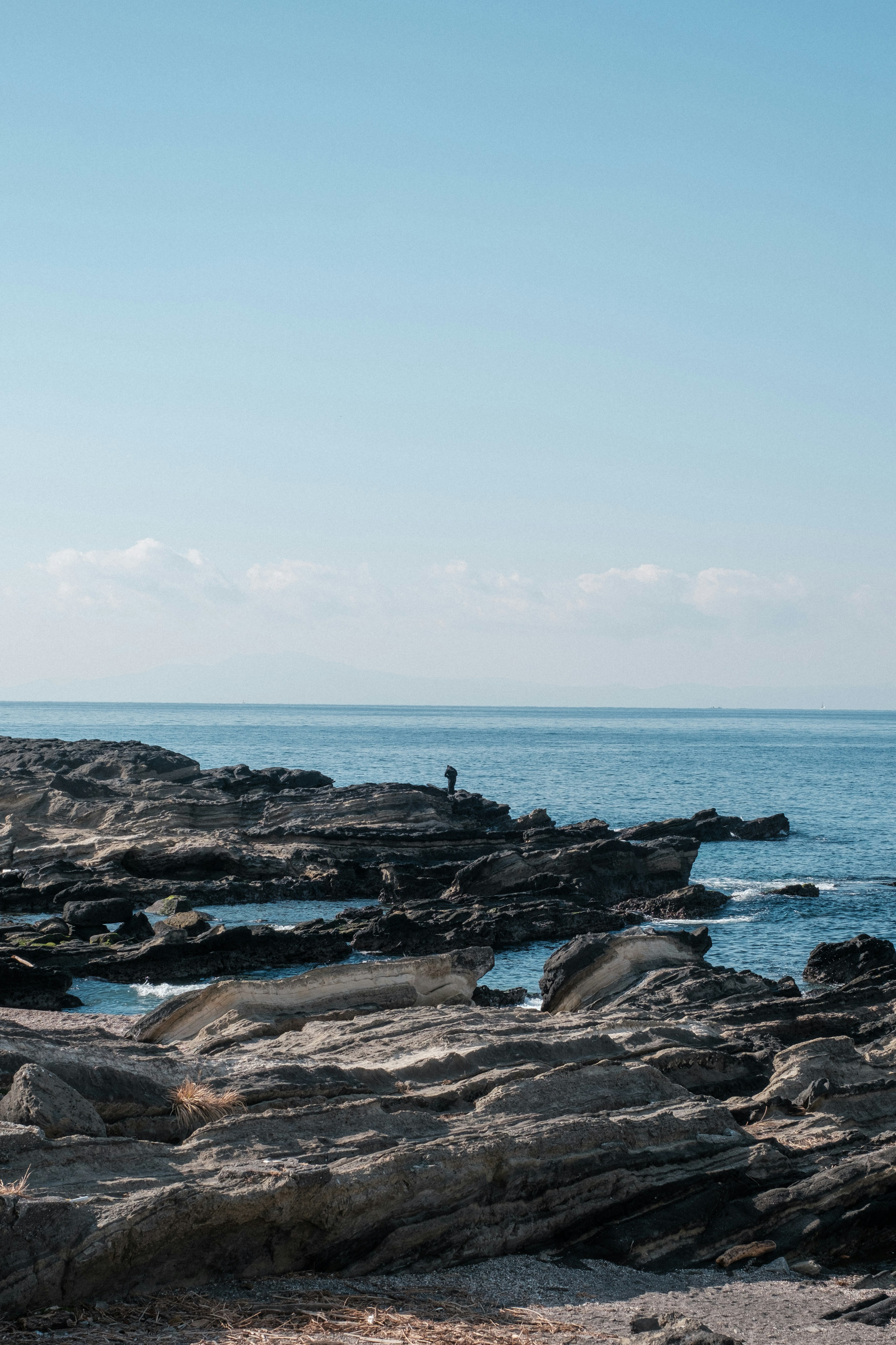 Mer bleue et côte rocheuse avec une silhouette au loin