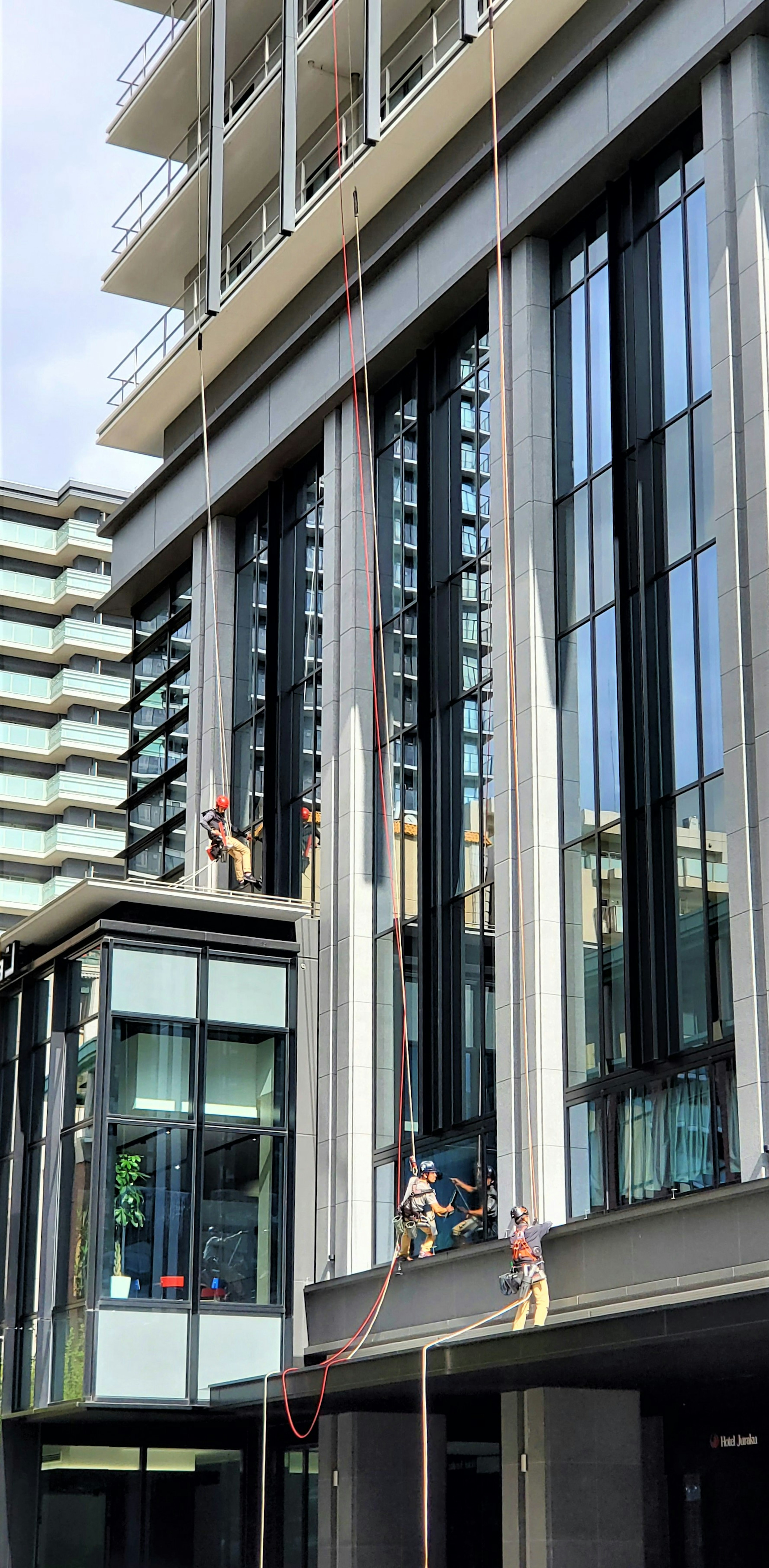 Window cleaners working on a high-rise building using ropes