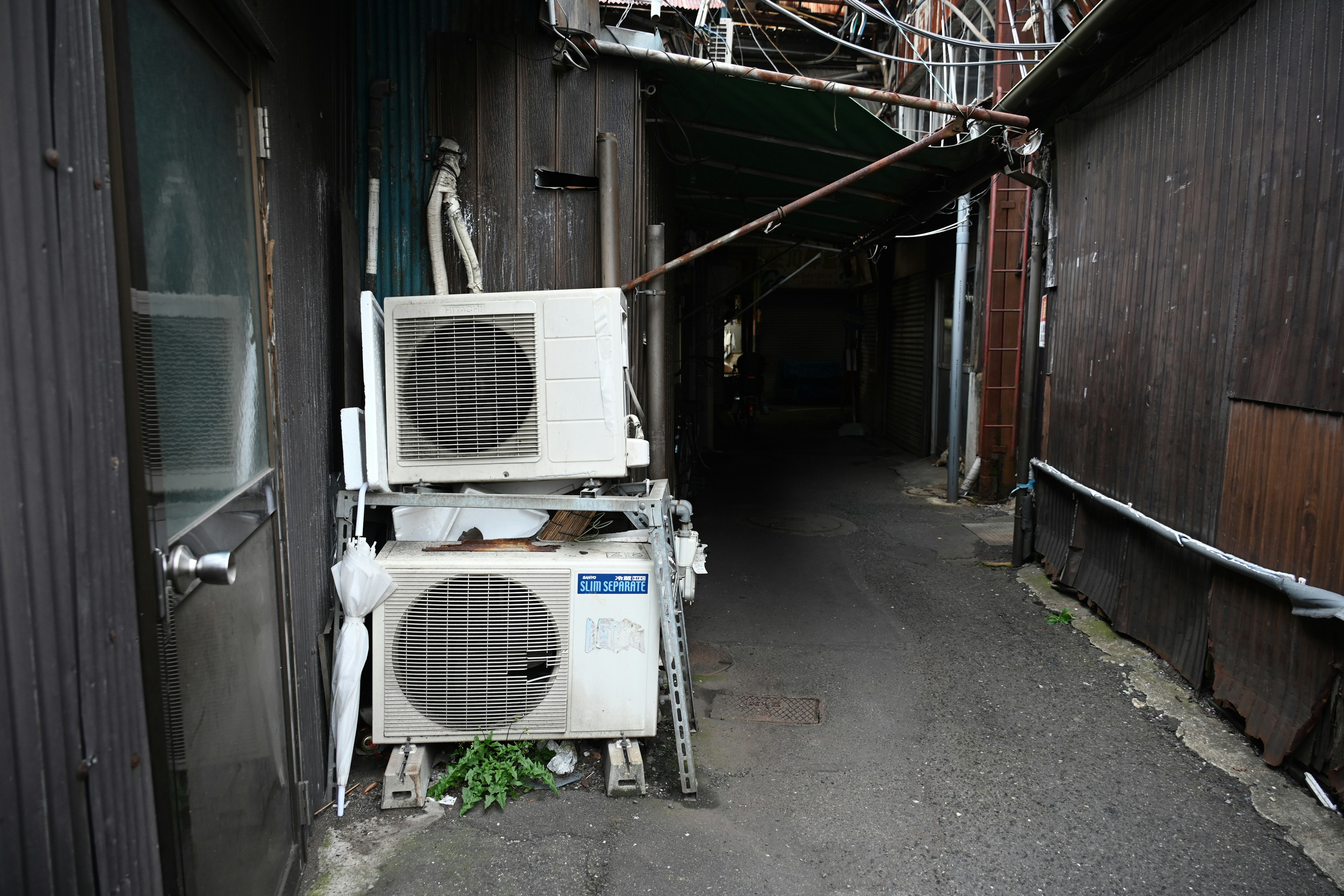 Unité de climatisation placée dans une ruelle étroite avec des murs en bois