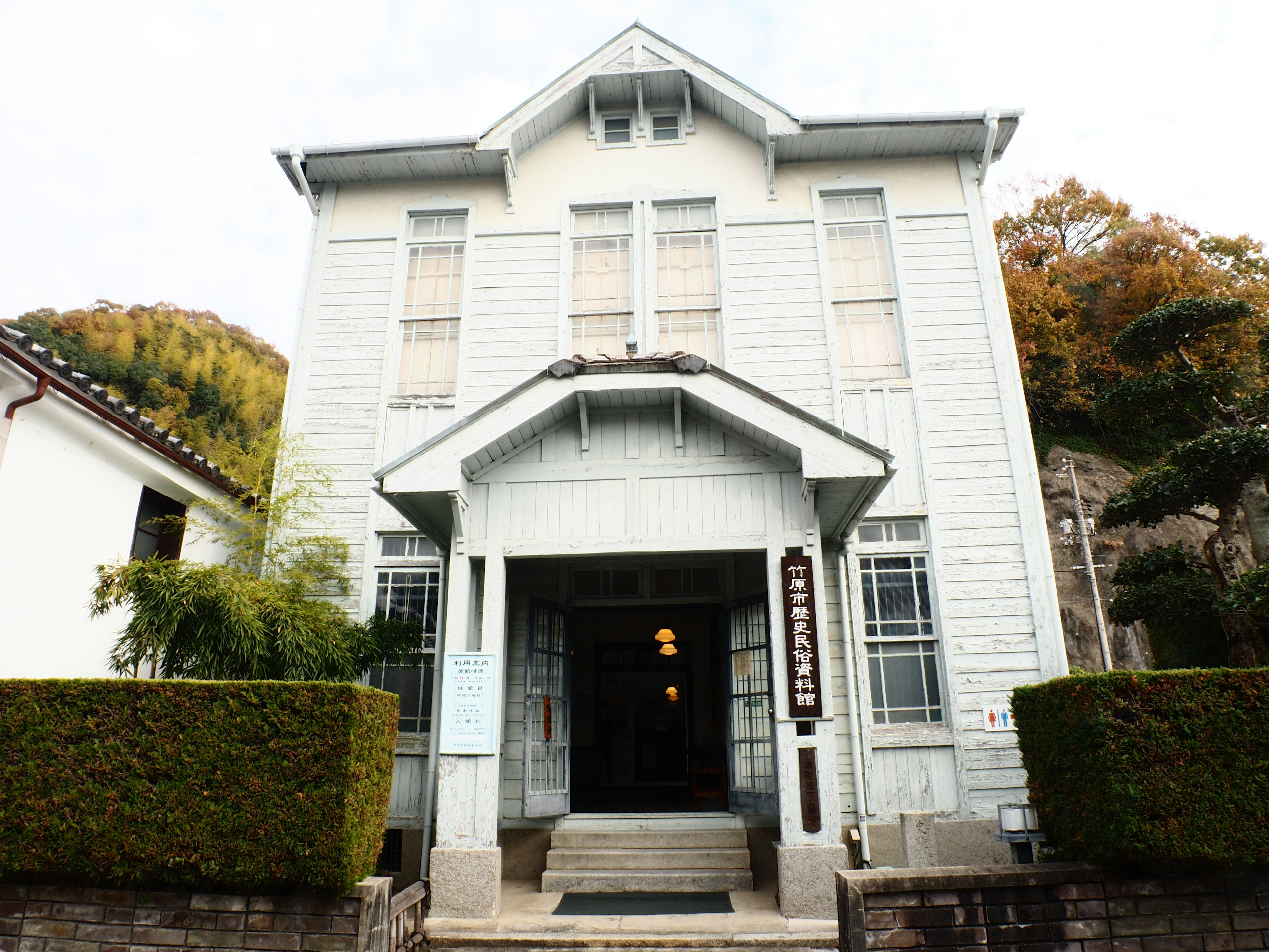 Historic building with white exterior featuring a central entrance and well-maintained garden