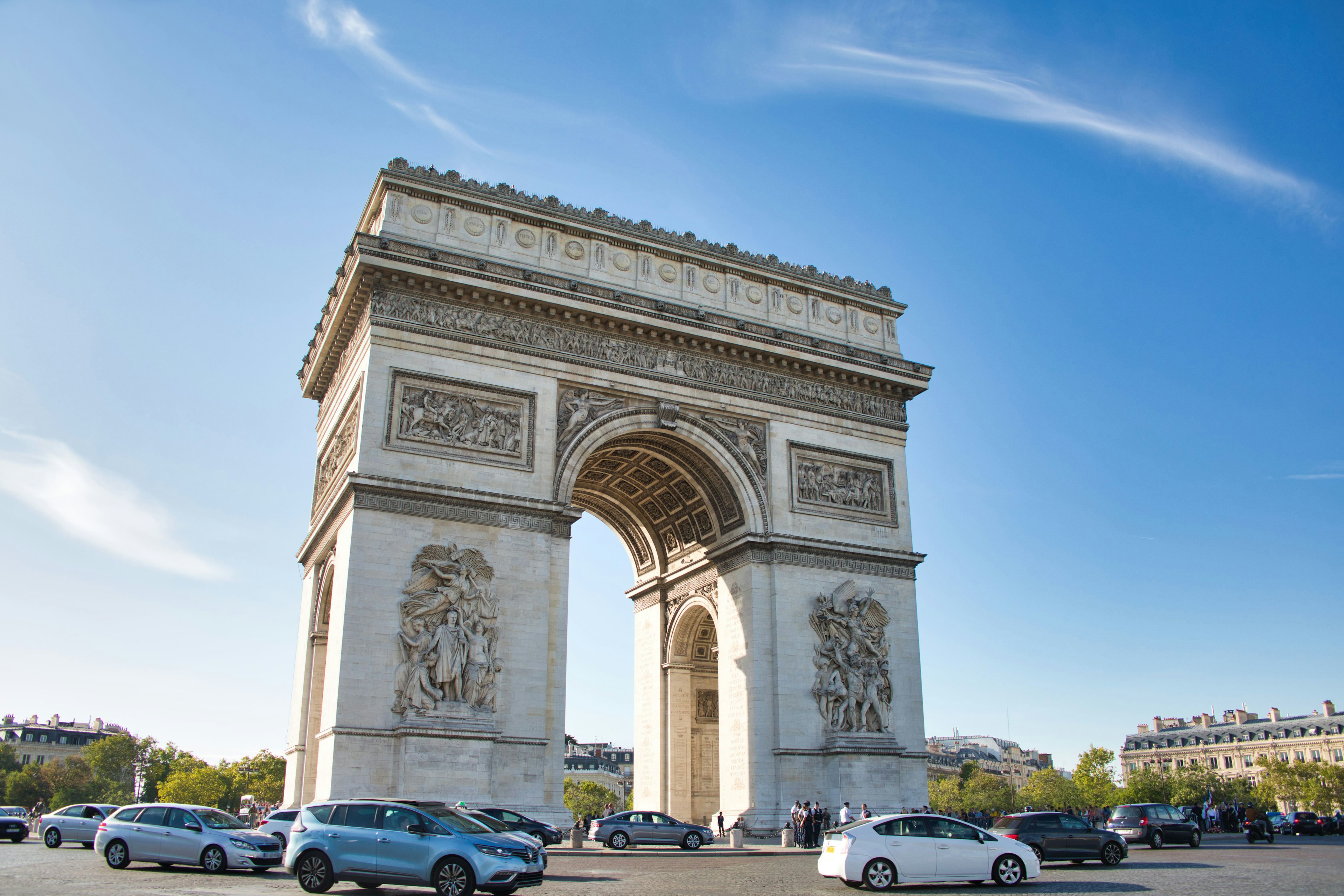 Schöner Blick auf den Arc de Triomphe in Paris historisches Denkmal unter blauem Himmel umgeben von Autos und grünen Bäumen