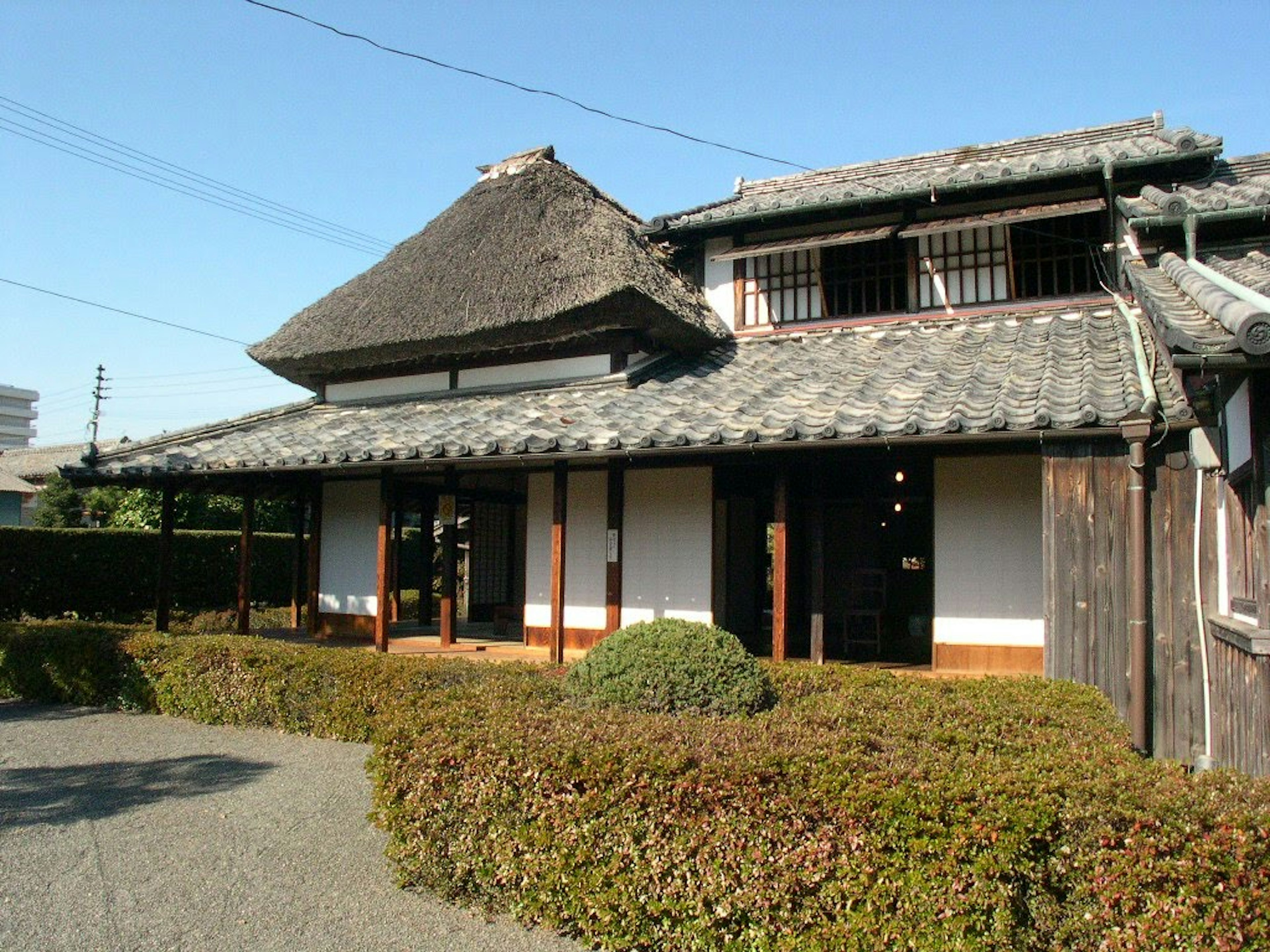 Extérieur d'une maison japonaise traditionnelle avec toit de chaume et murs en bois