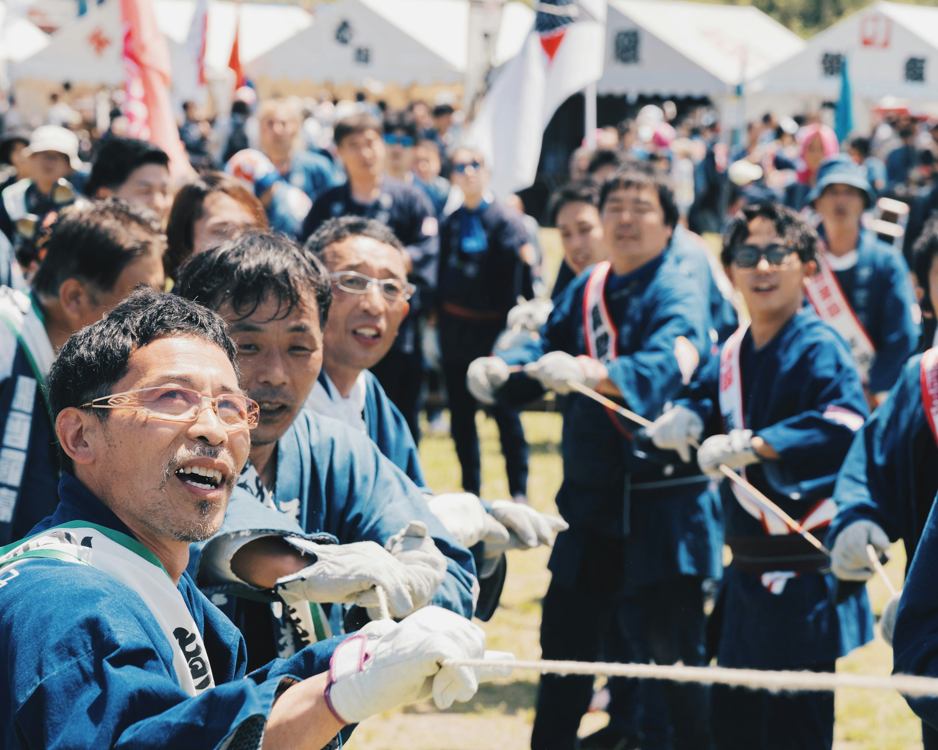 祭りの参加者が笑顔で綱引きをしている様子