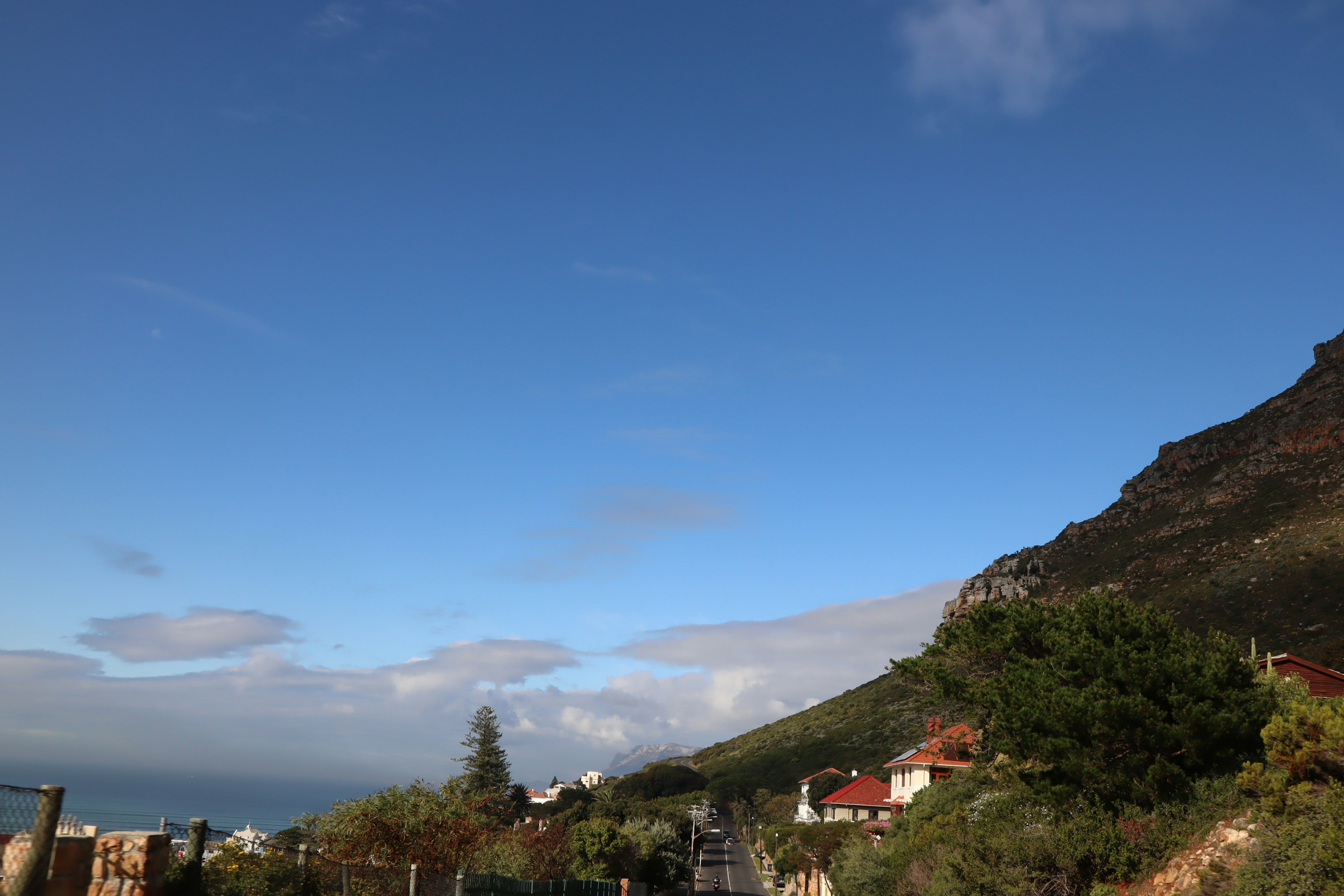 Vista escénica que presenta un cielo azul con nubes y montañas junto a casas