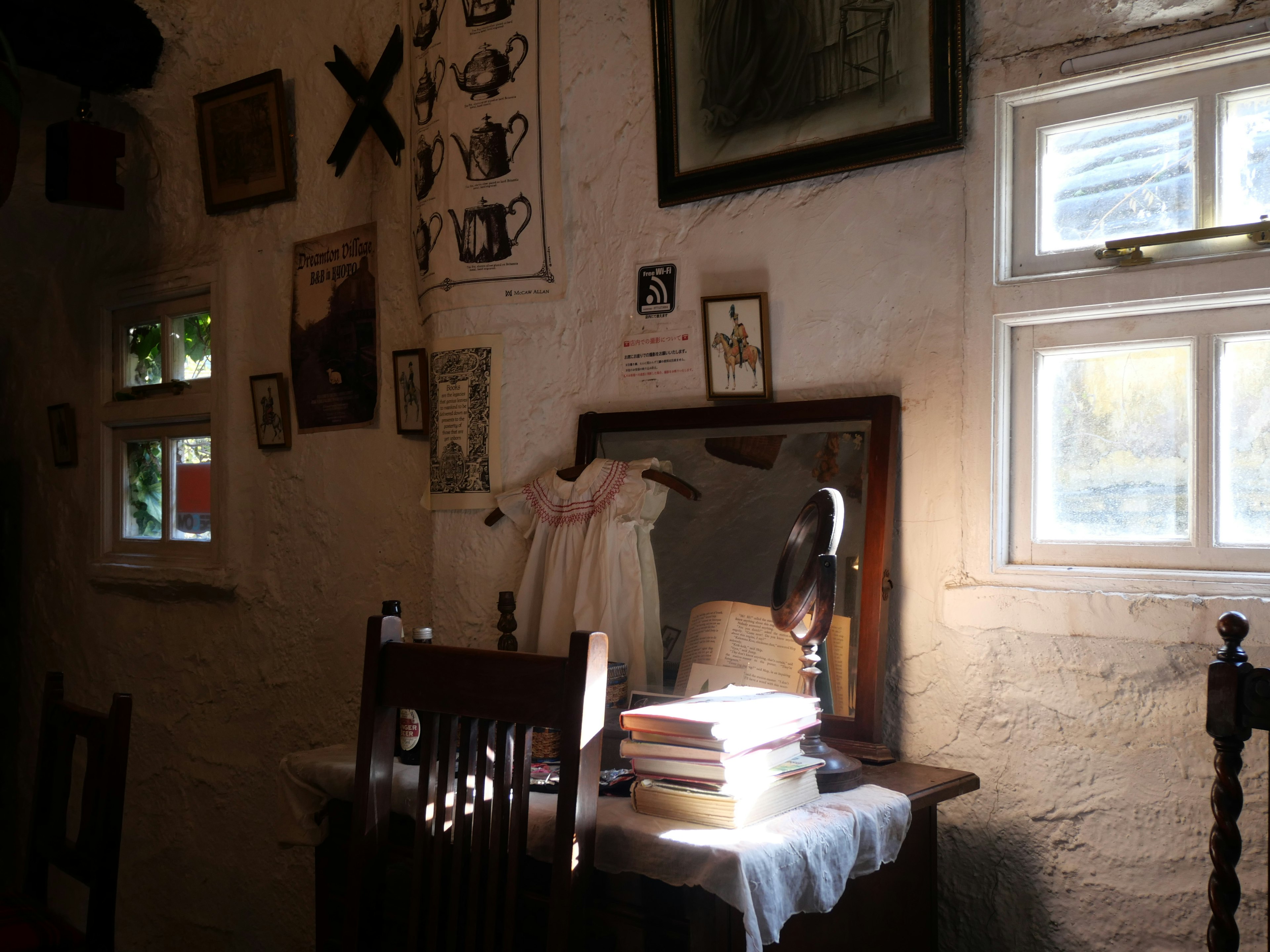 Intérieur d'une petite pièce avec la lumière du soleil entrant mettant en avant une table en bois et une chaise avec un miroir et des livres