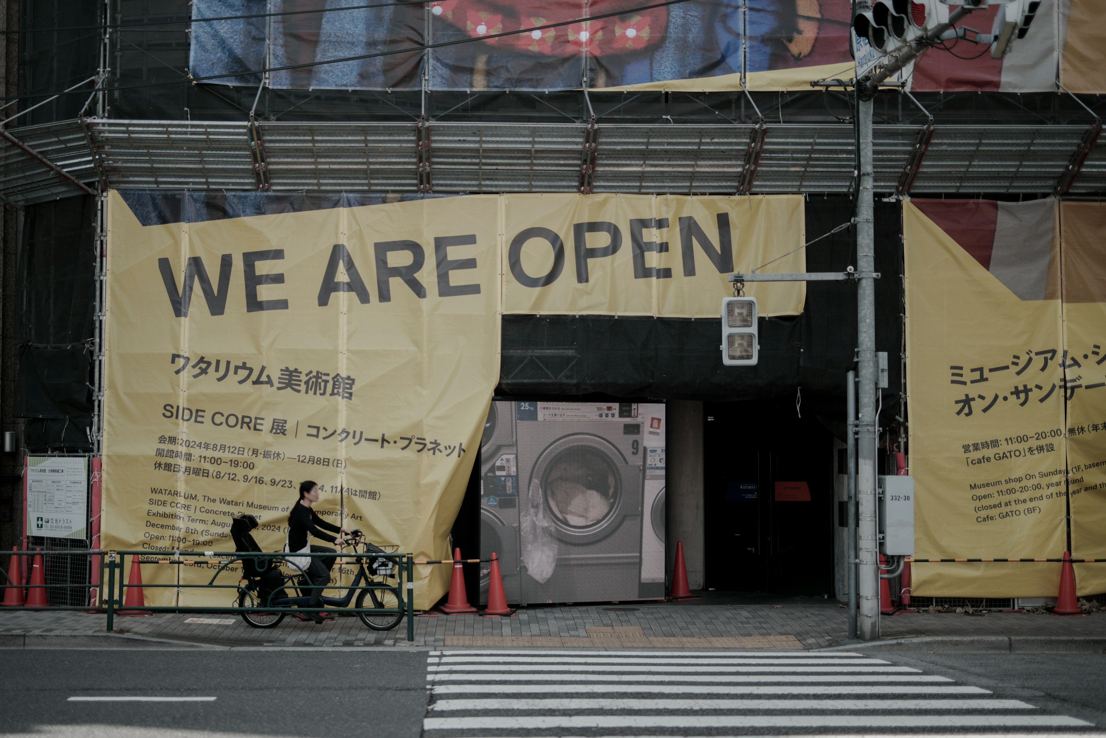 Exterior de un edificio comercial con una gran pancarta que dice estamos abiertos