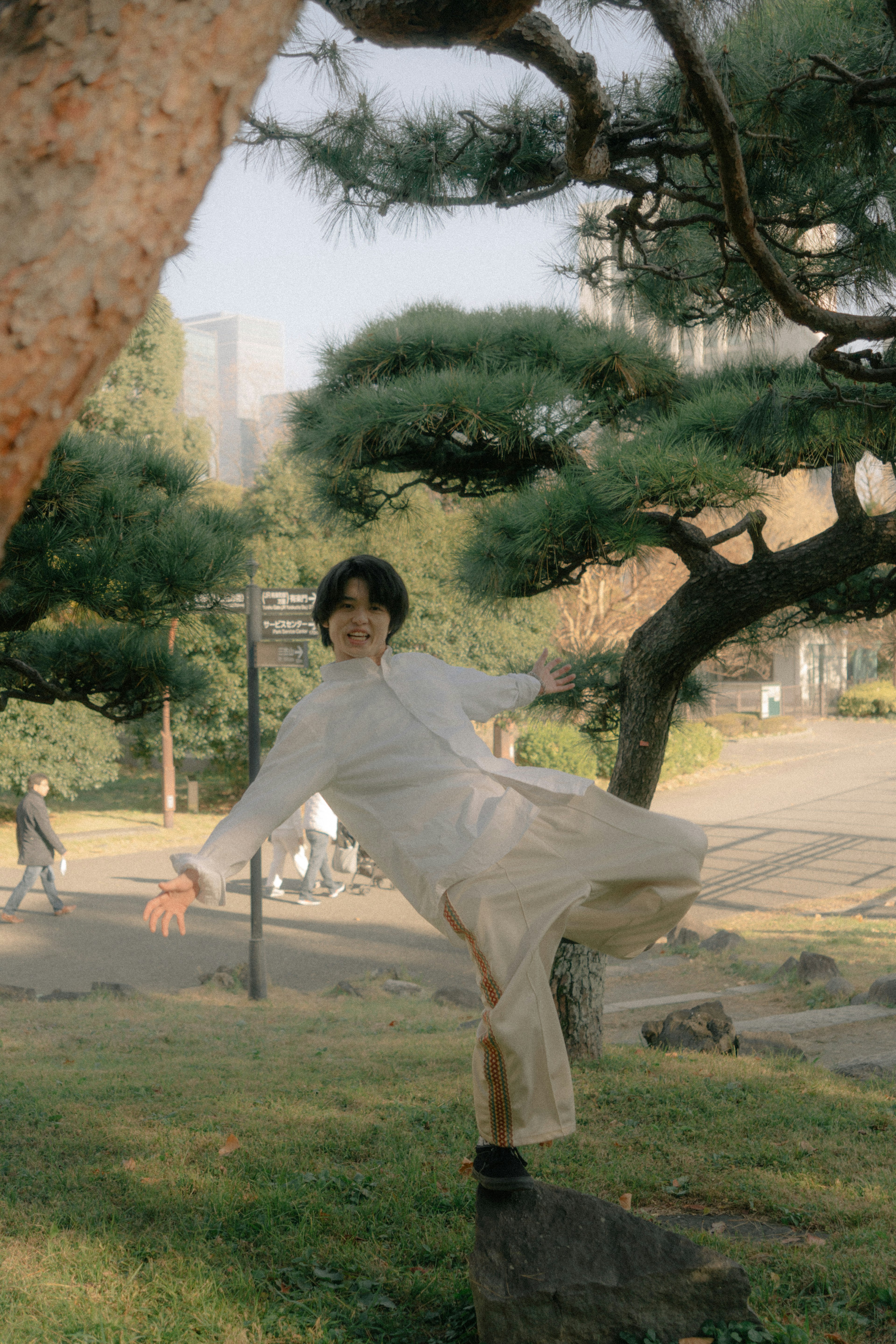 公園の木の近くでポーズをとる若い女性