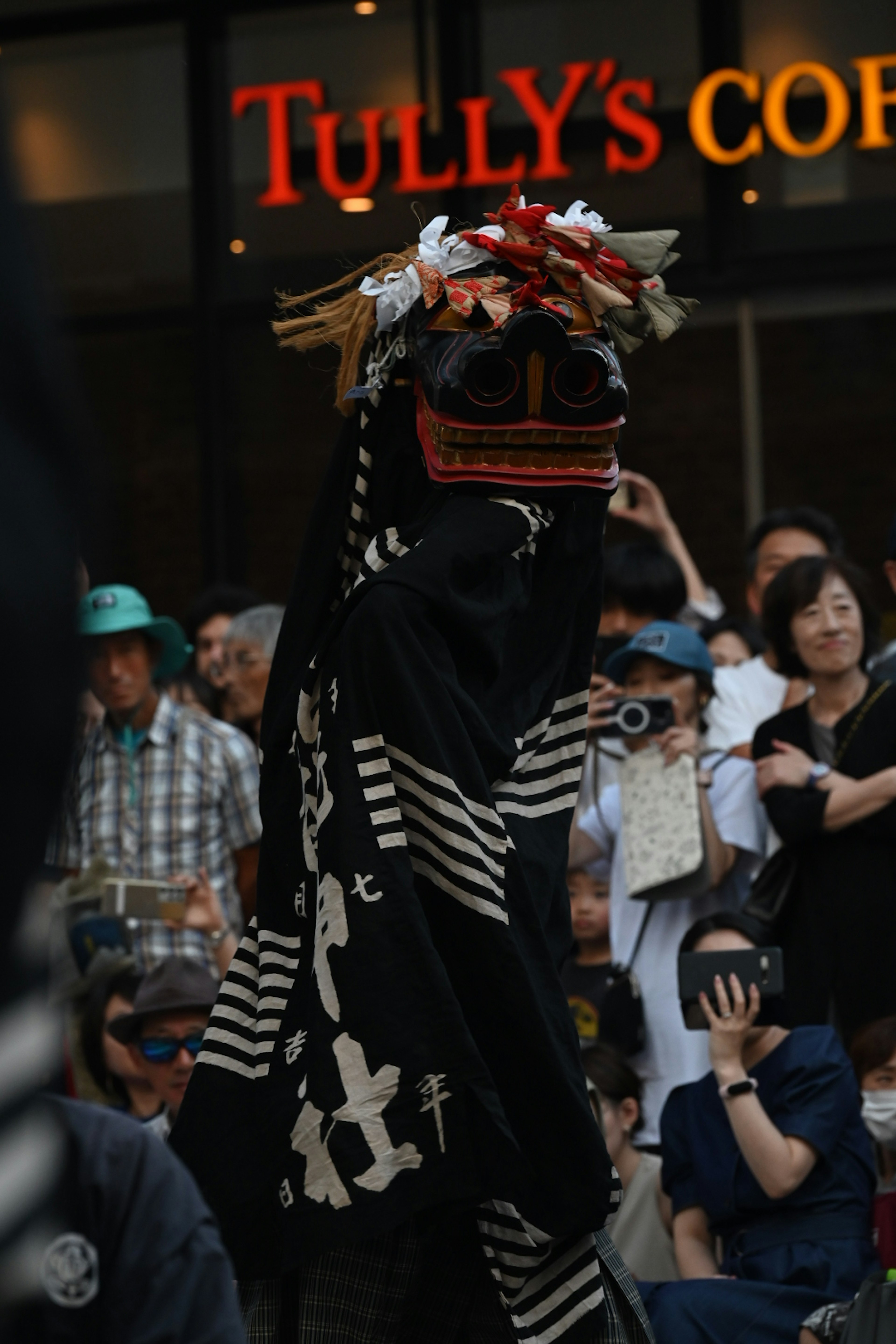 Una persona con vestimenta tradicional actuando frente a Tully's Coffee