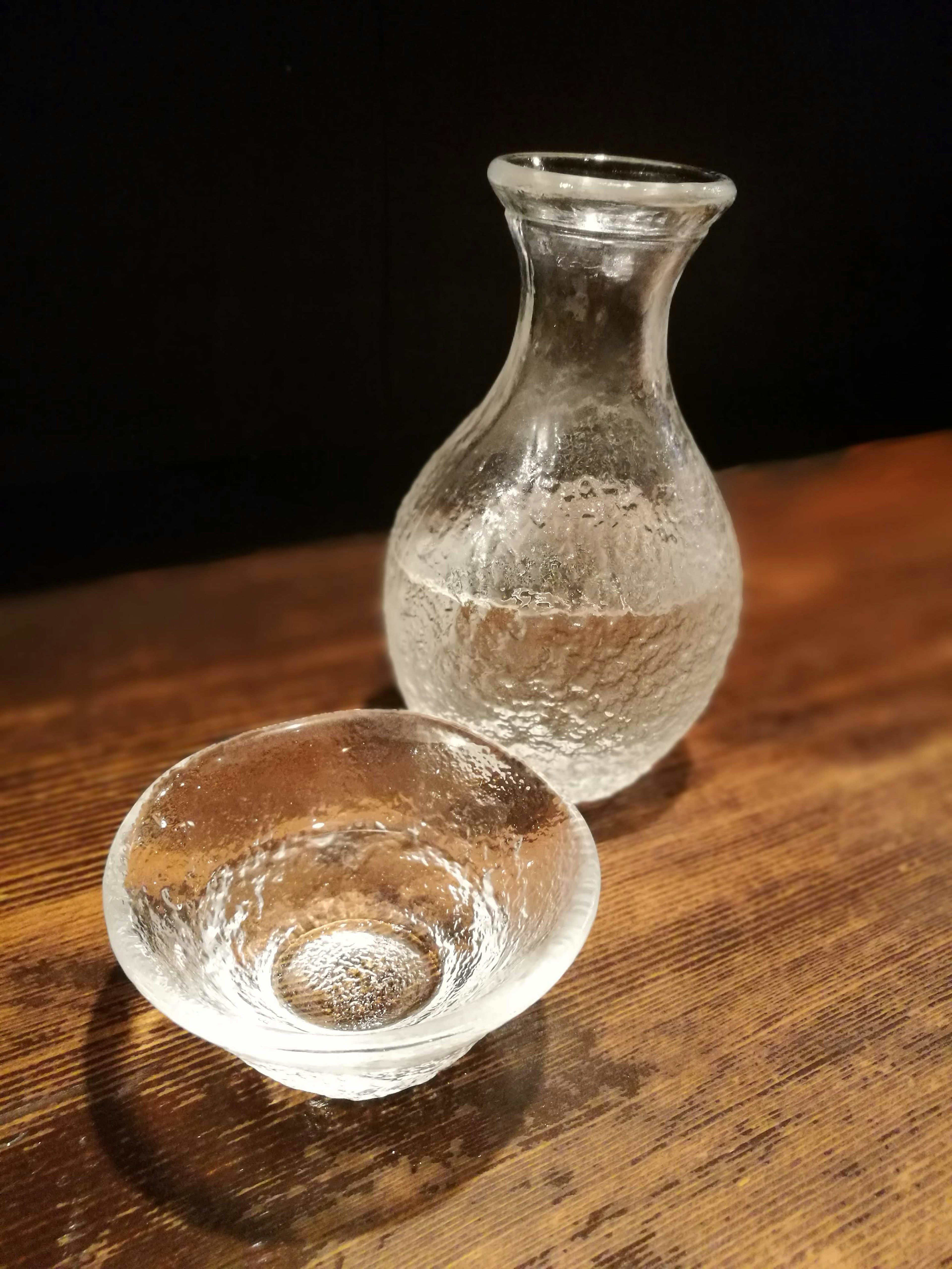 Un pichet en verre transparent et un petit bol posés sur une table en bois