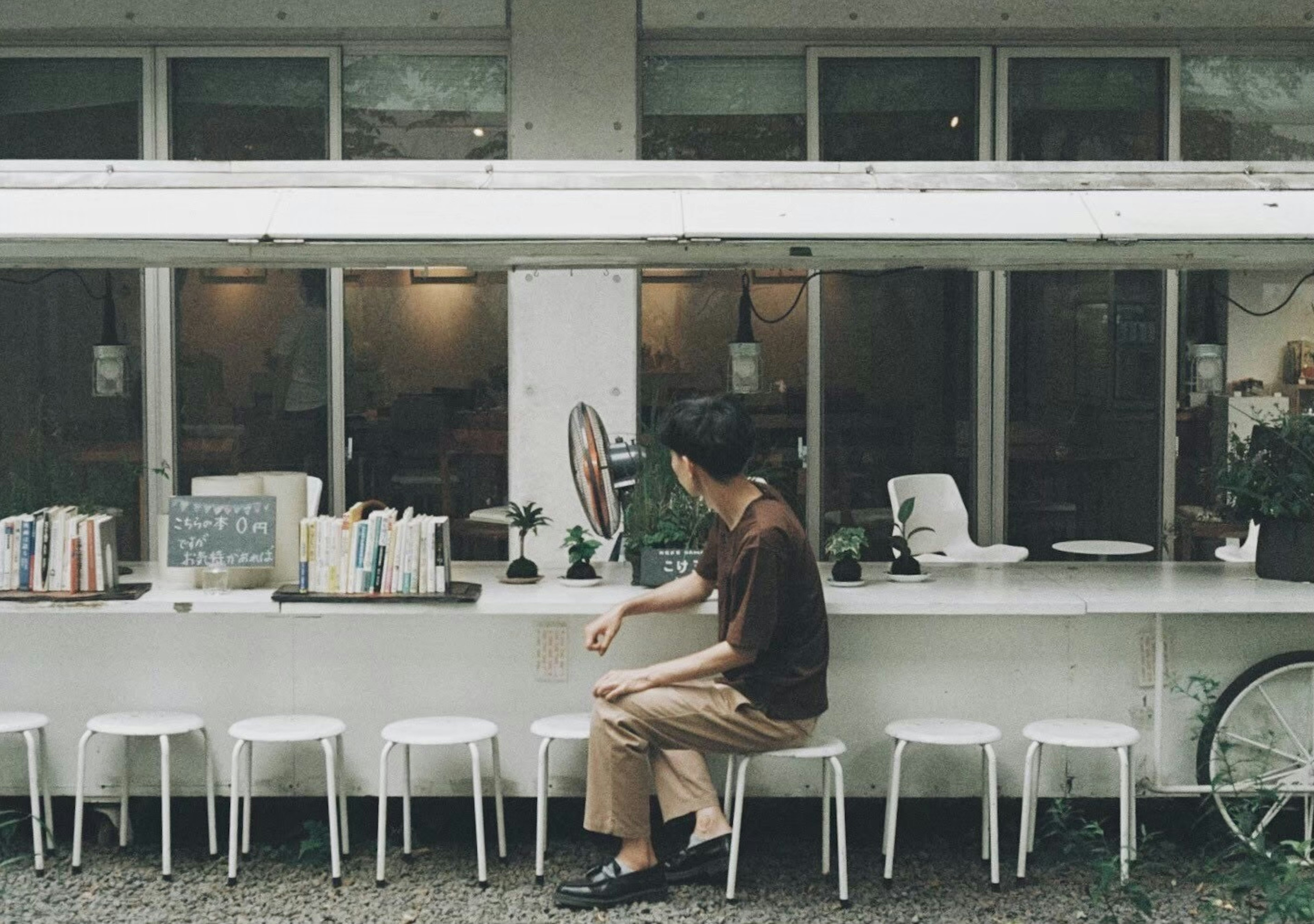 Person sitting at a white table in a cafe with books around