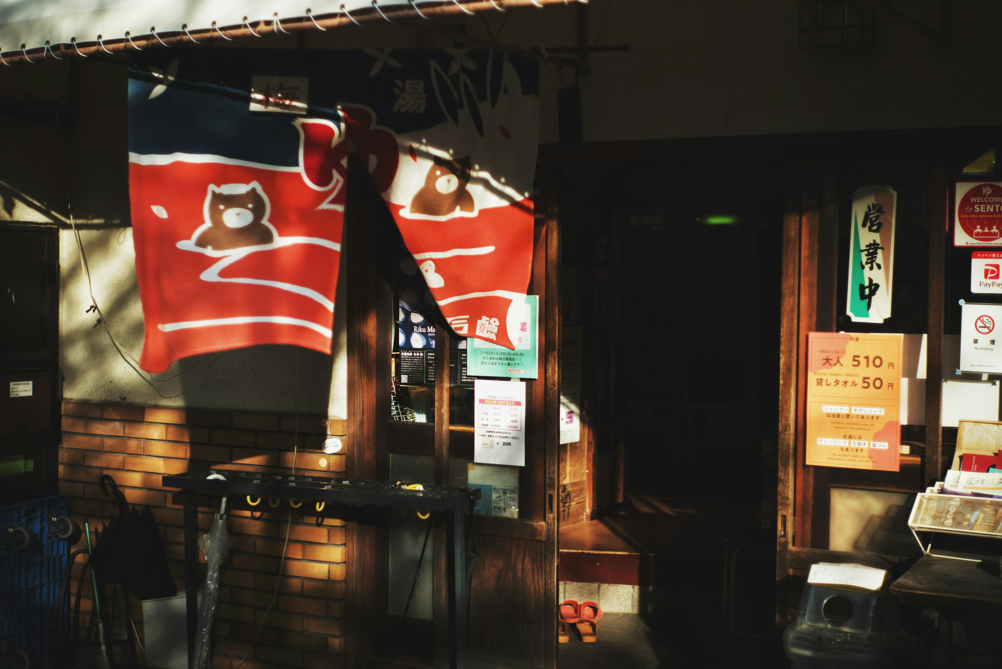 Entrada de tienda japonesa con noren rojo que presenta un diseño de búho