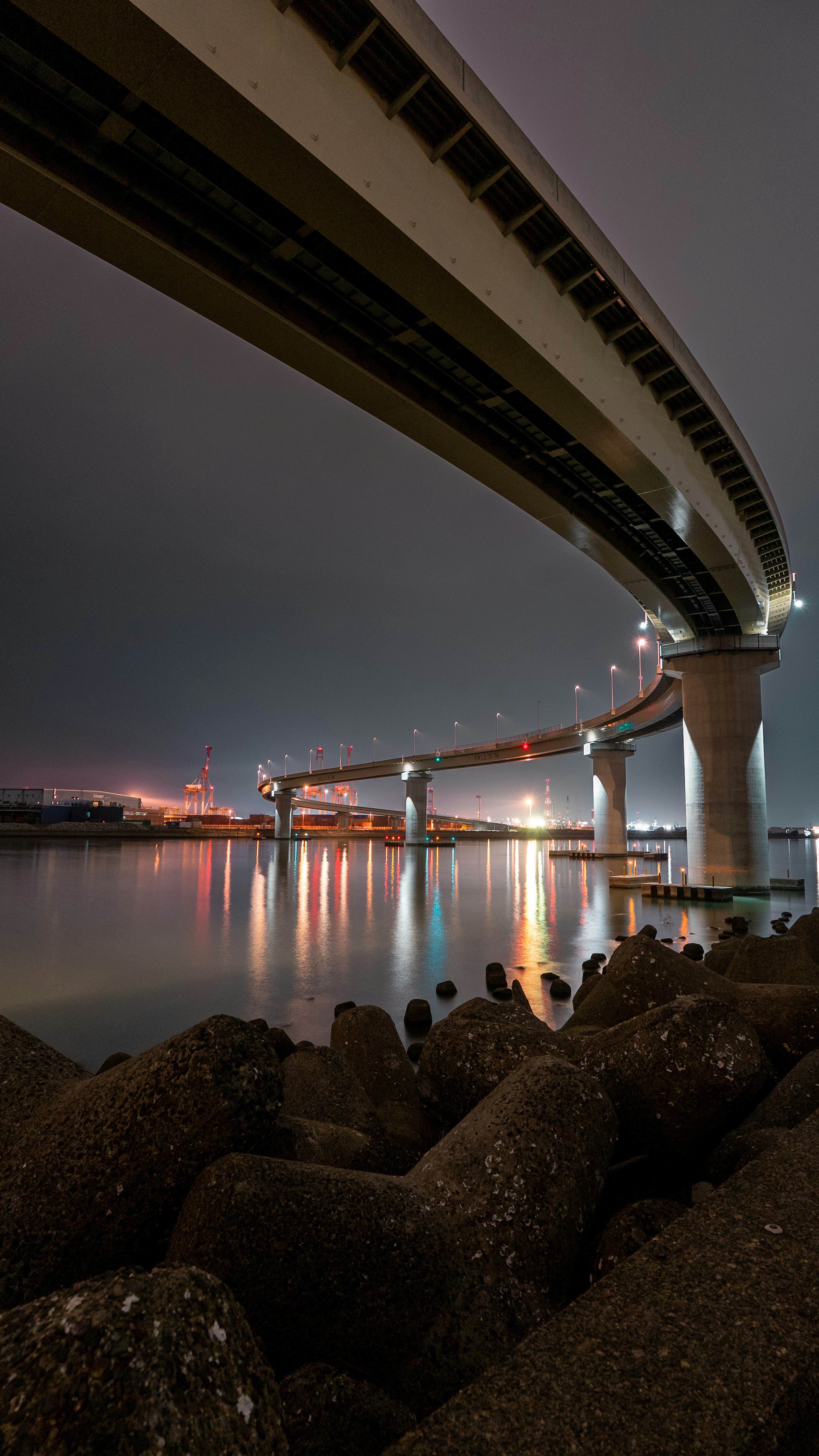 Pemandangan dari bawah jembatan jalan raya di atas sungai di malam hari dengan pantulan yang indah