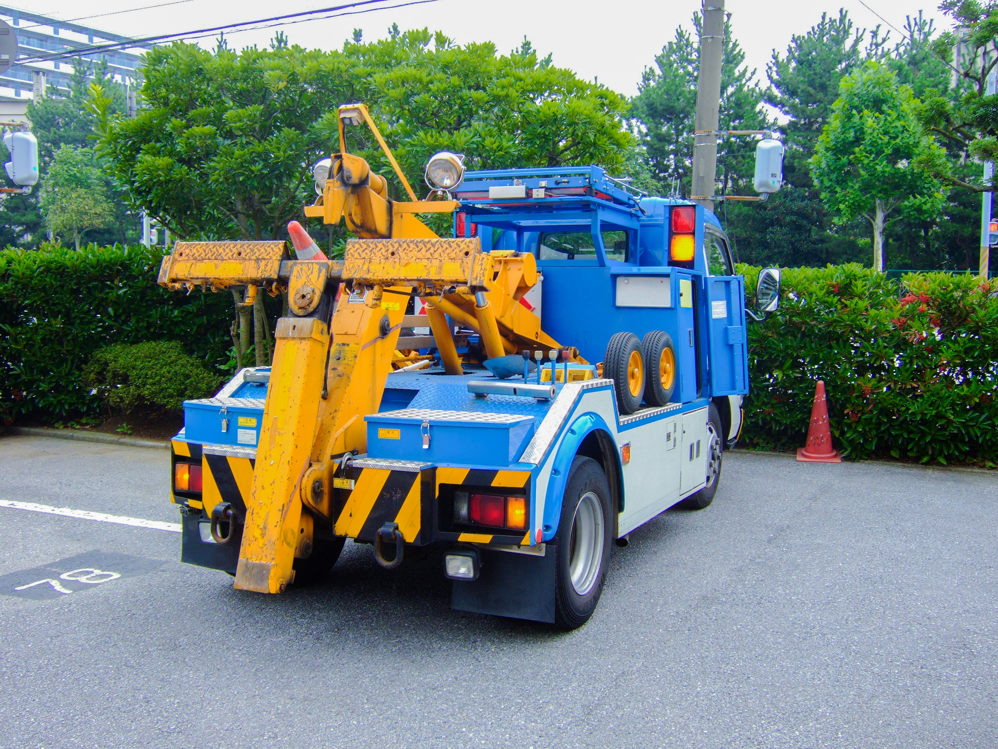 Un camion bleu avec une grue jaune attachée garé dans une zone verte