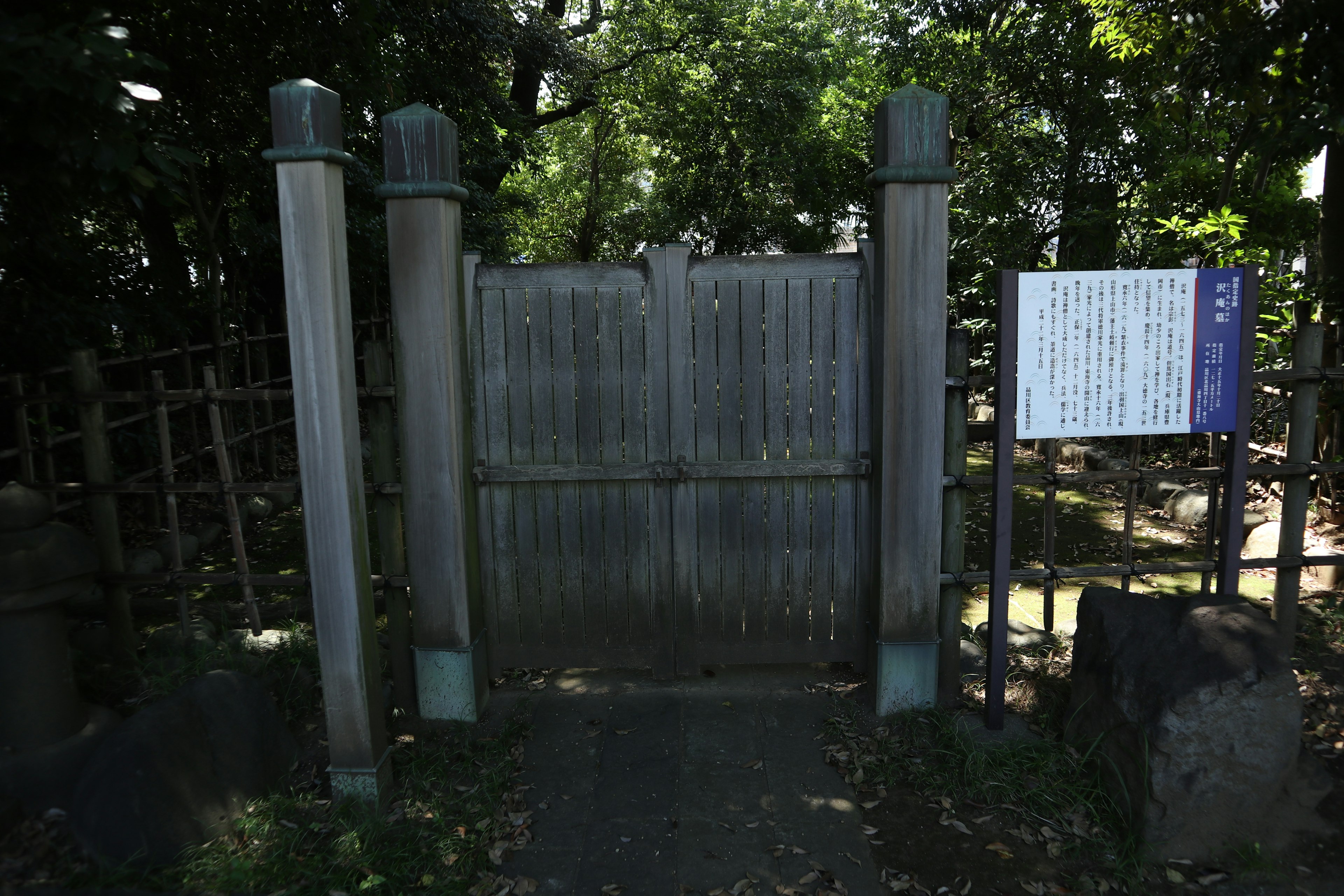 Old wooden gate surrounded by greenery with an information board