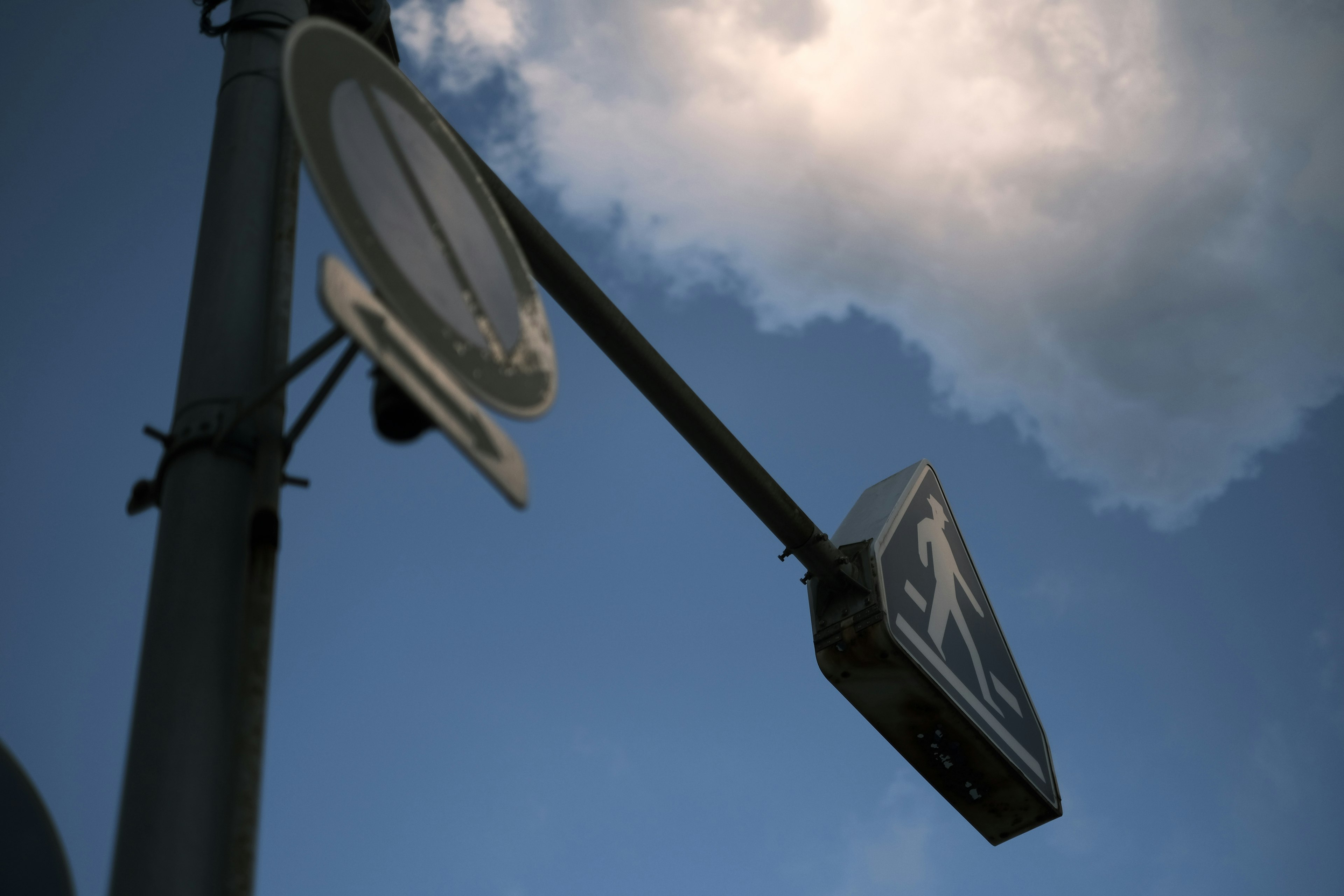 Tilted pedestrian signal against a blue sky