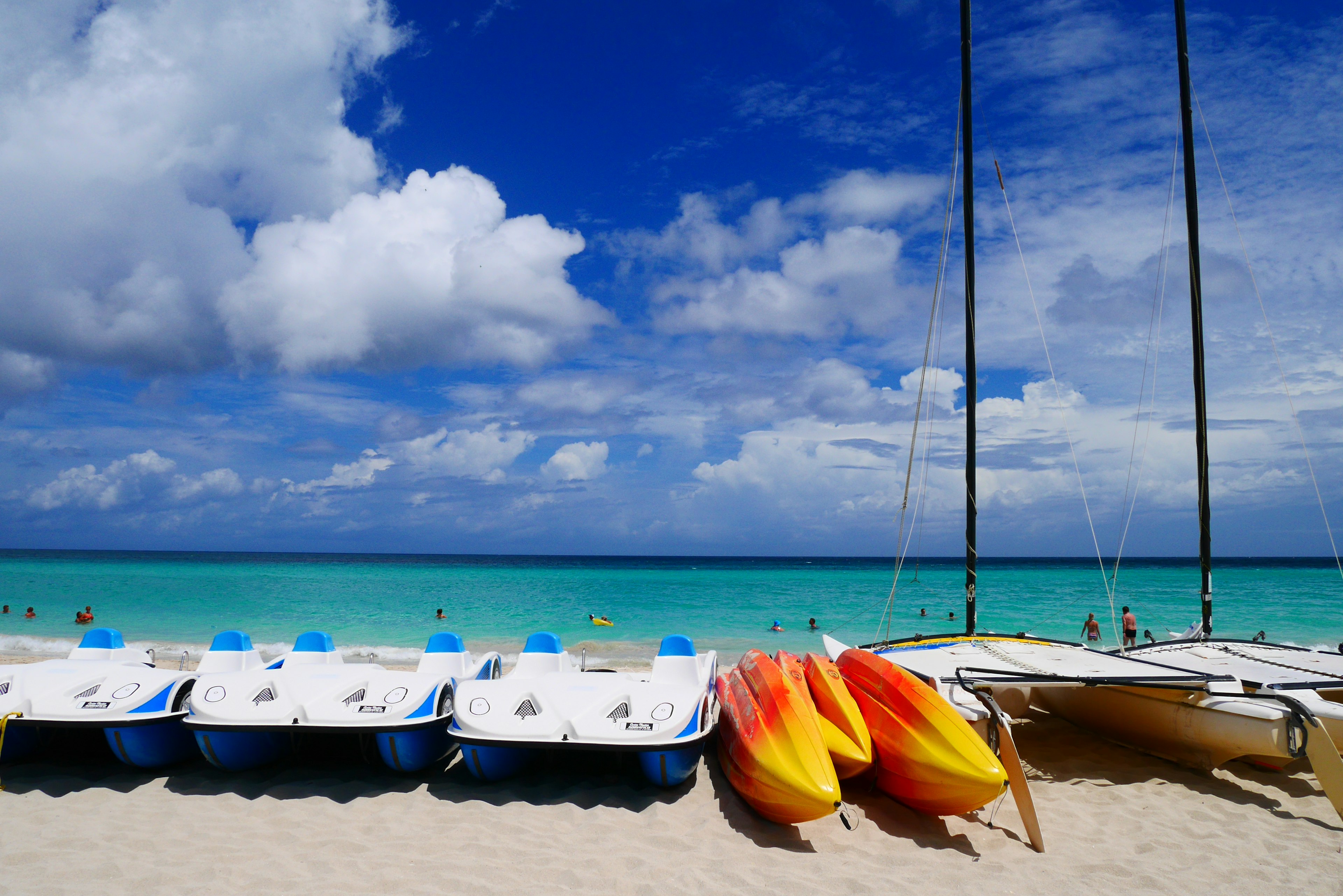 Kayaks colorés et bateaux sur une plage de sable avec une mer bleue vibrante