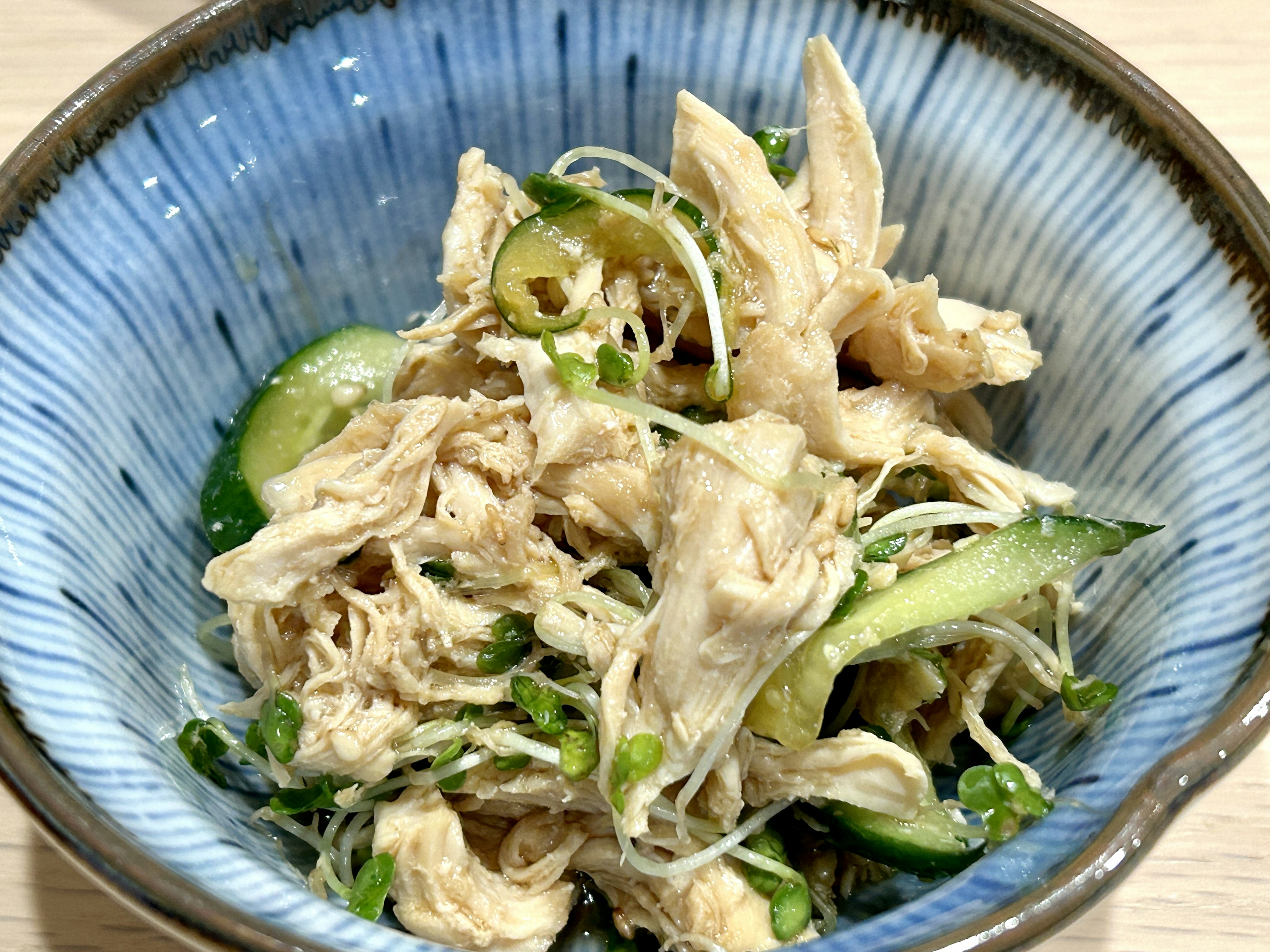 Shredded chicken salad with cucumbers in a blue bowl