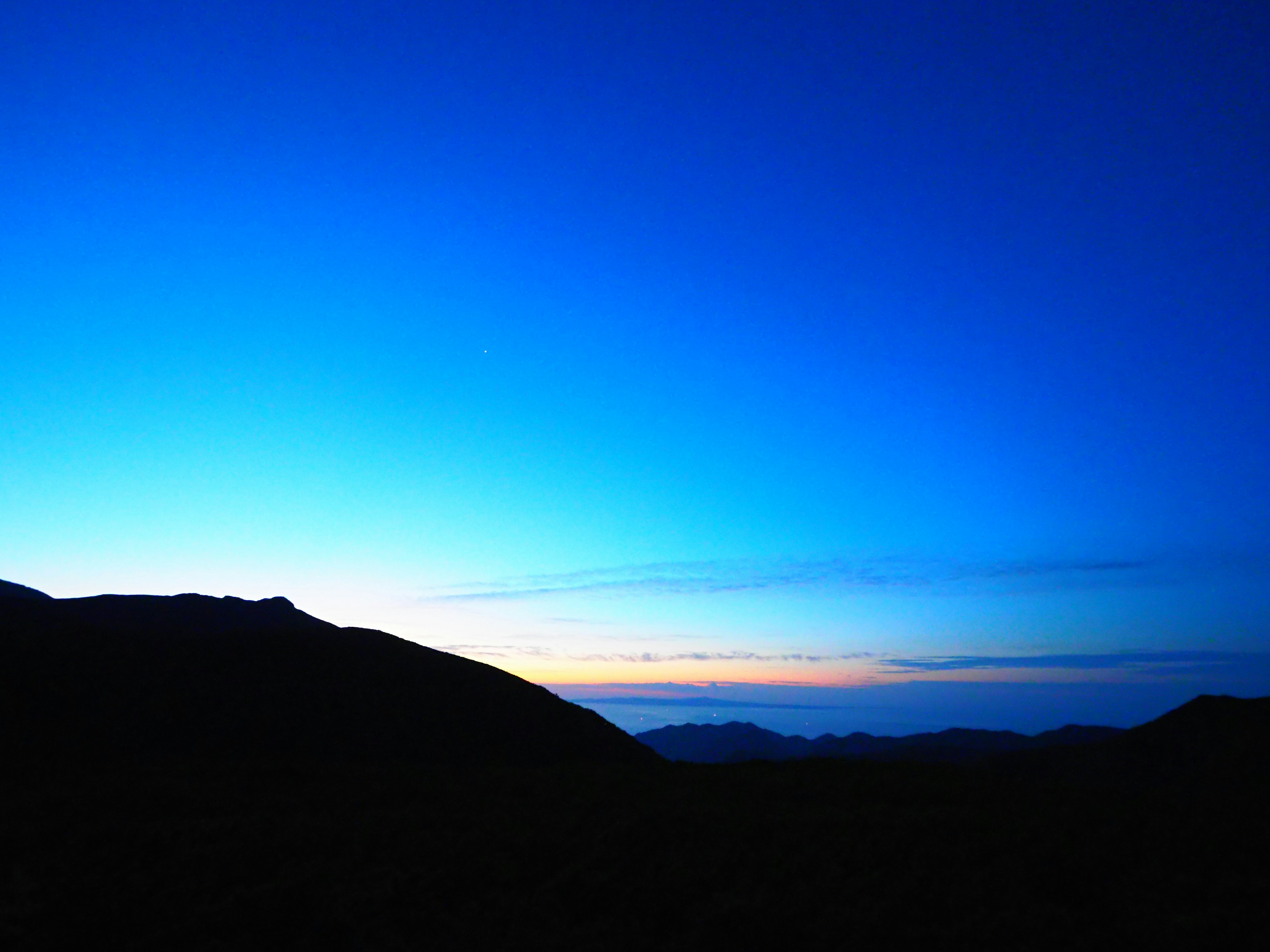 山のシルエットと青い空が広がる風景