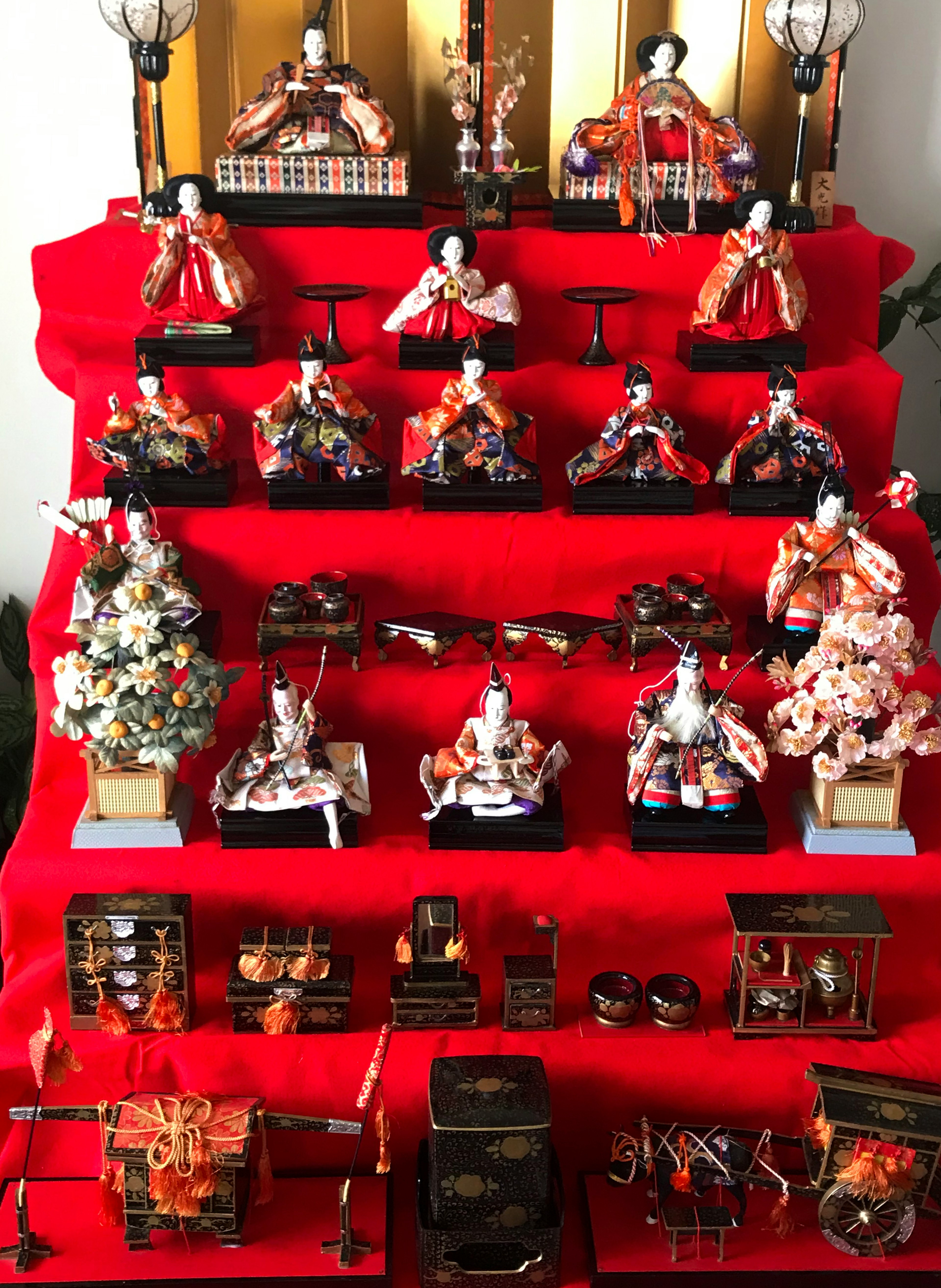 Display of hina dolls and decorations arranged on a red cloth