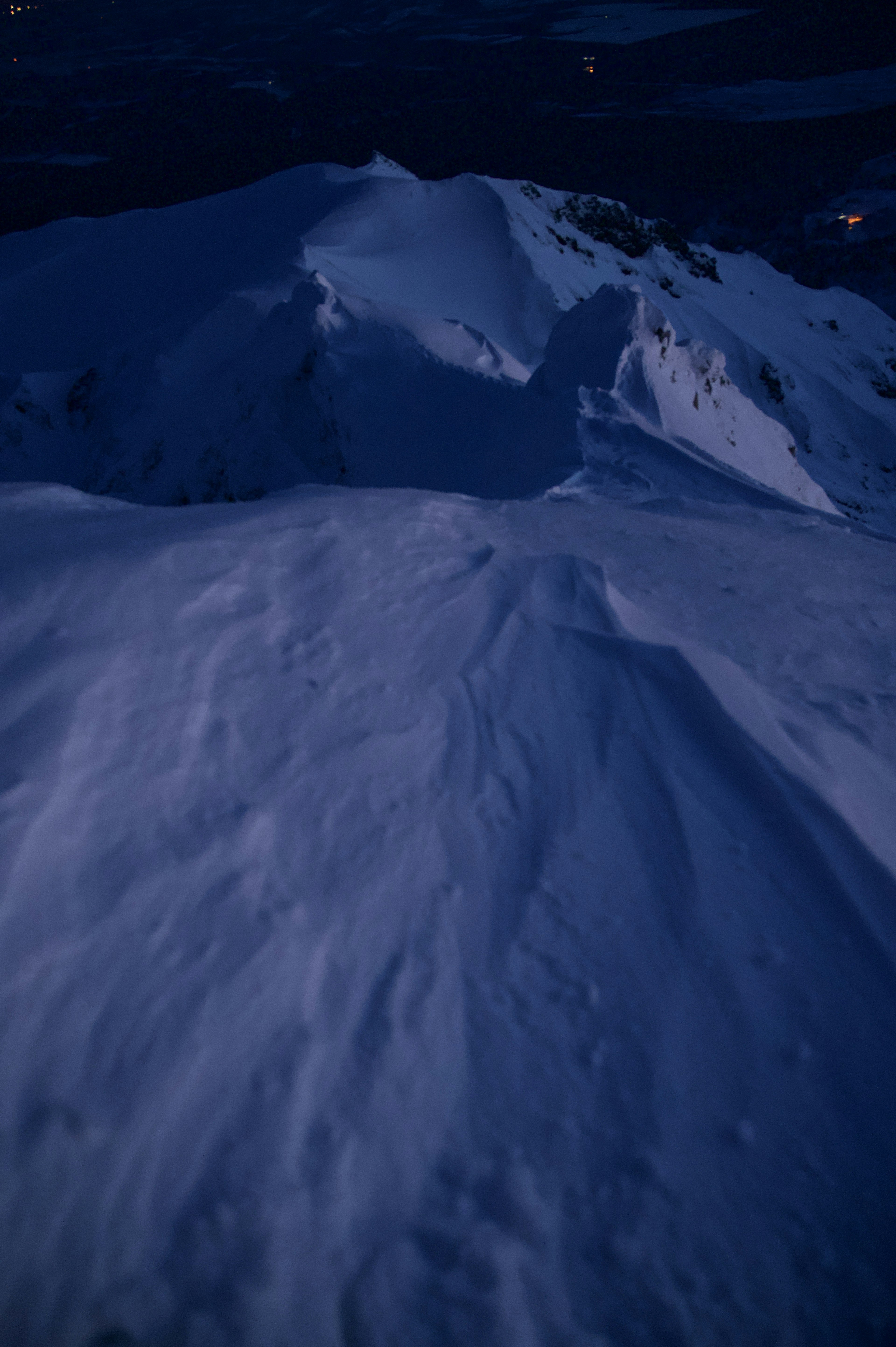 Glatte Schneefläche eines Berges bei Nacht mit schattigen Konturen