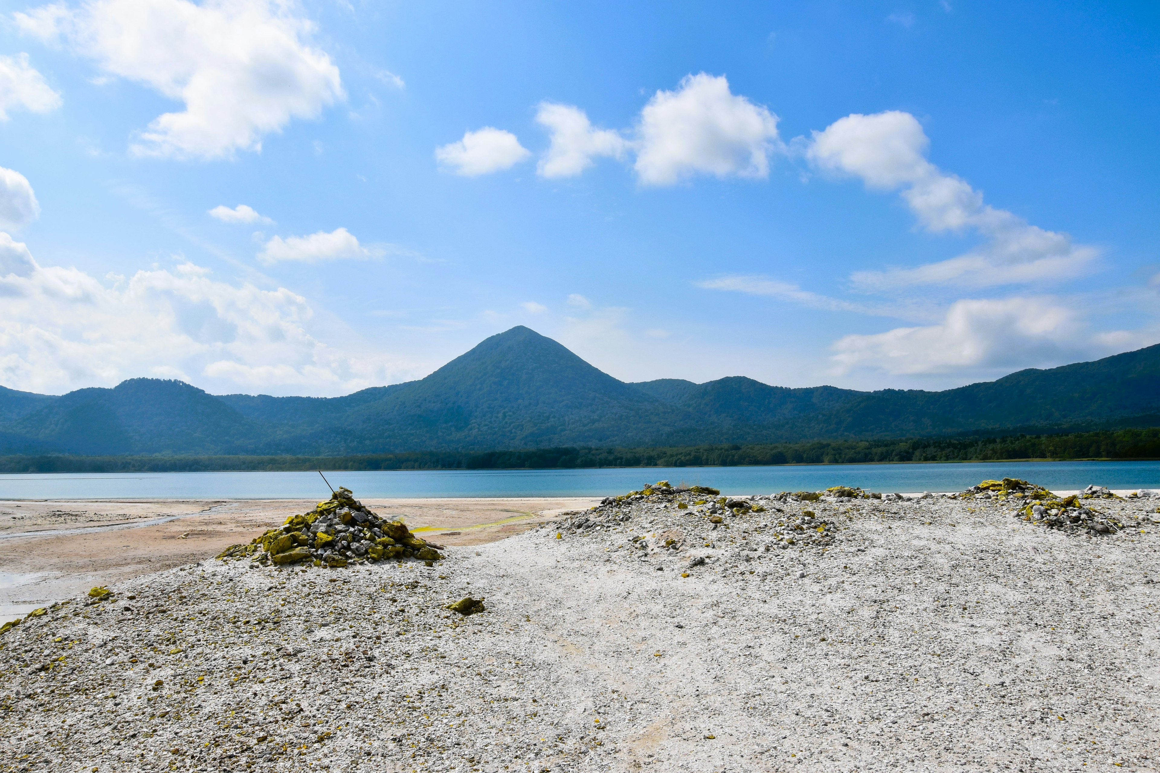 青い空と白い雲の下に広がる美しい湖と山の風景