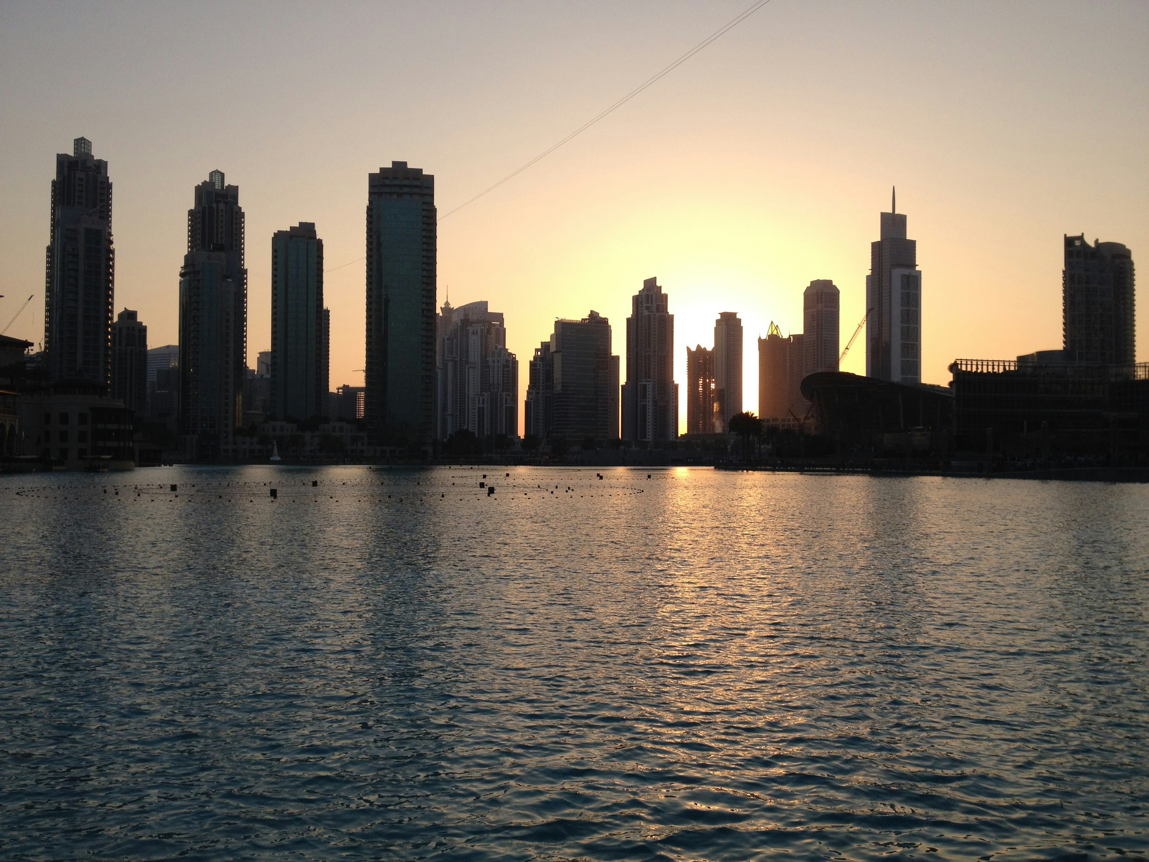 Silhouette of skyscrapers against the sunset reflecting on the water