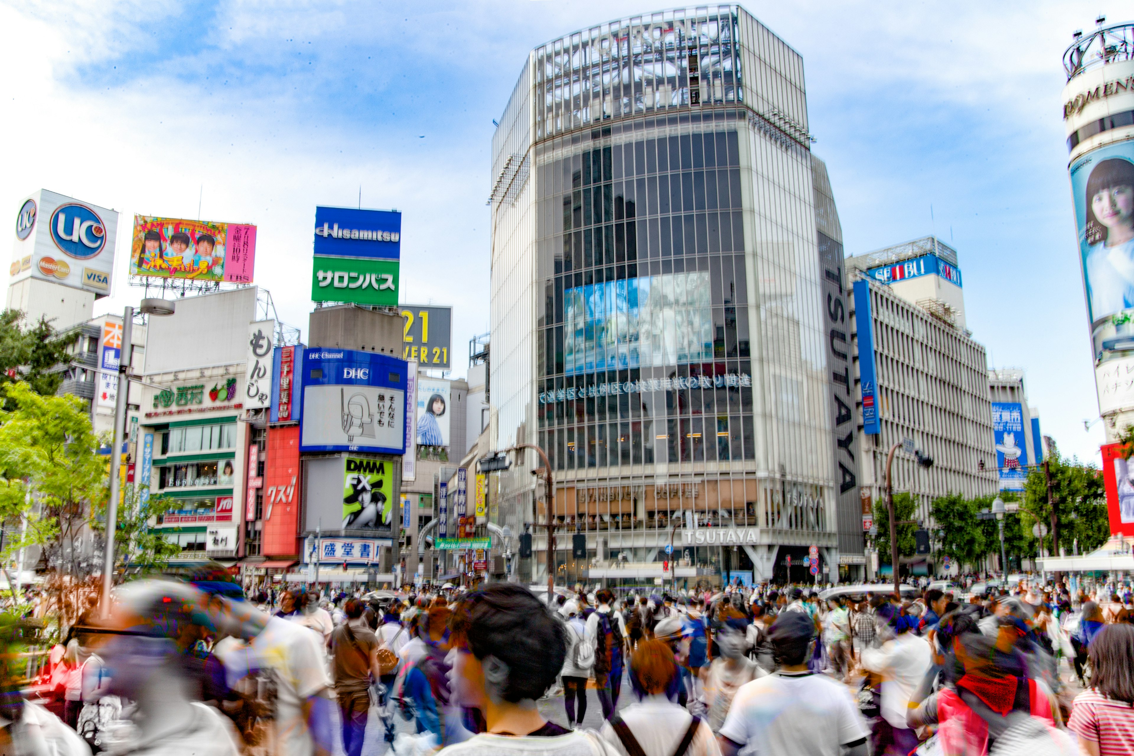 Busy Shibuya Crossing with numerous pedestrians and vibrant advertisements