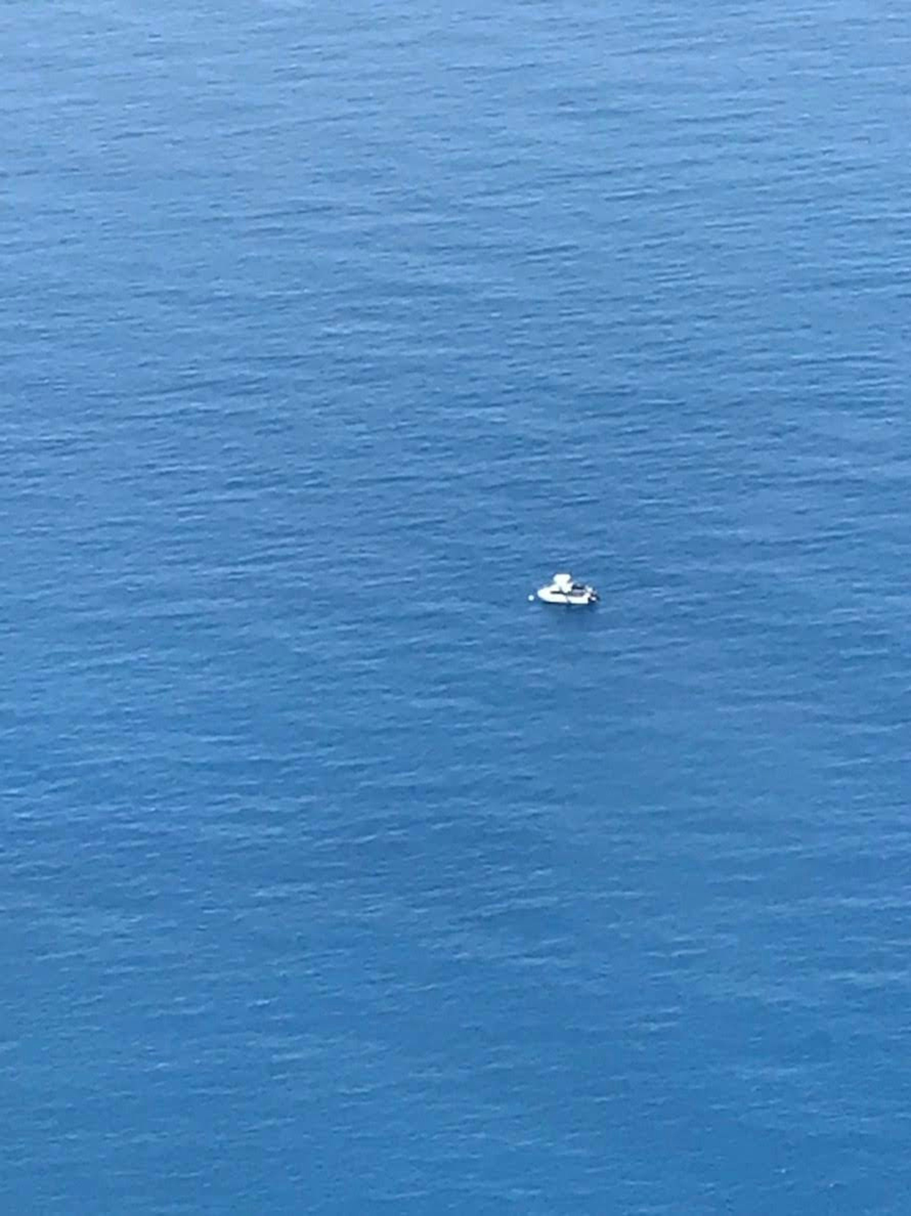 A small boat floating on a vast blue ocean