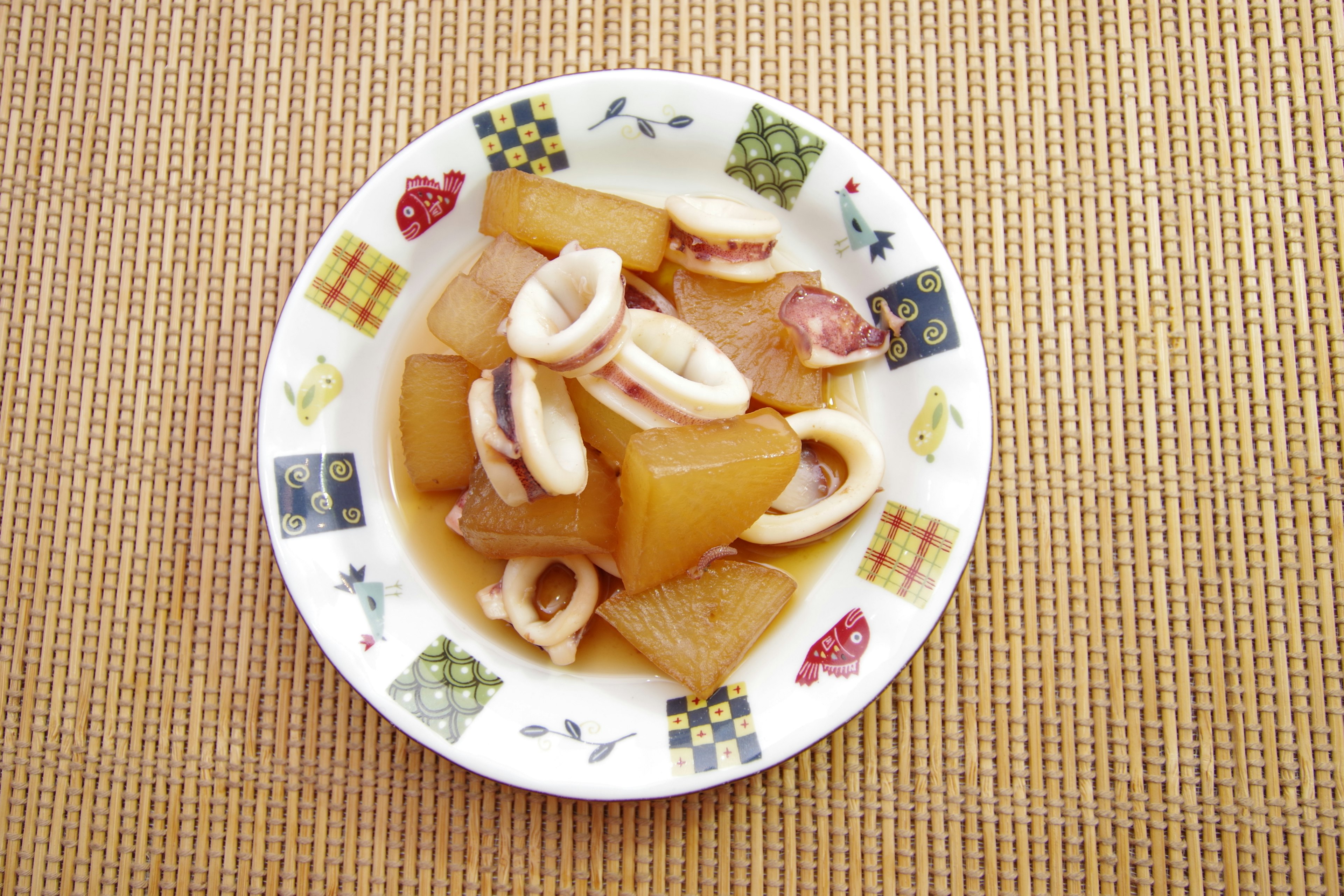 Un piatto di stufato di calamari e daikon guarnito con verdure