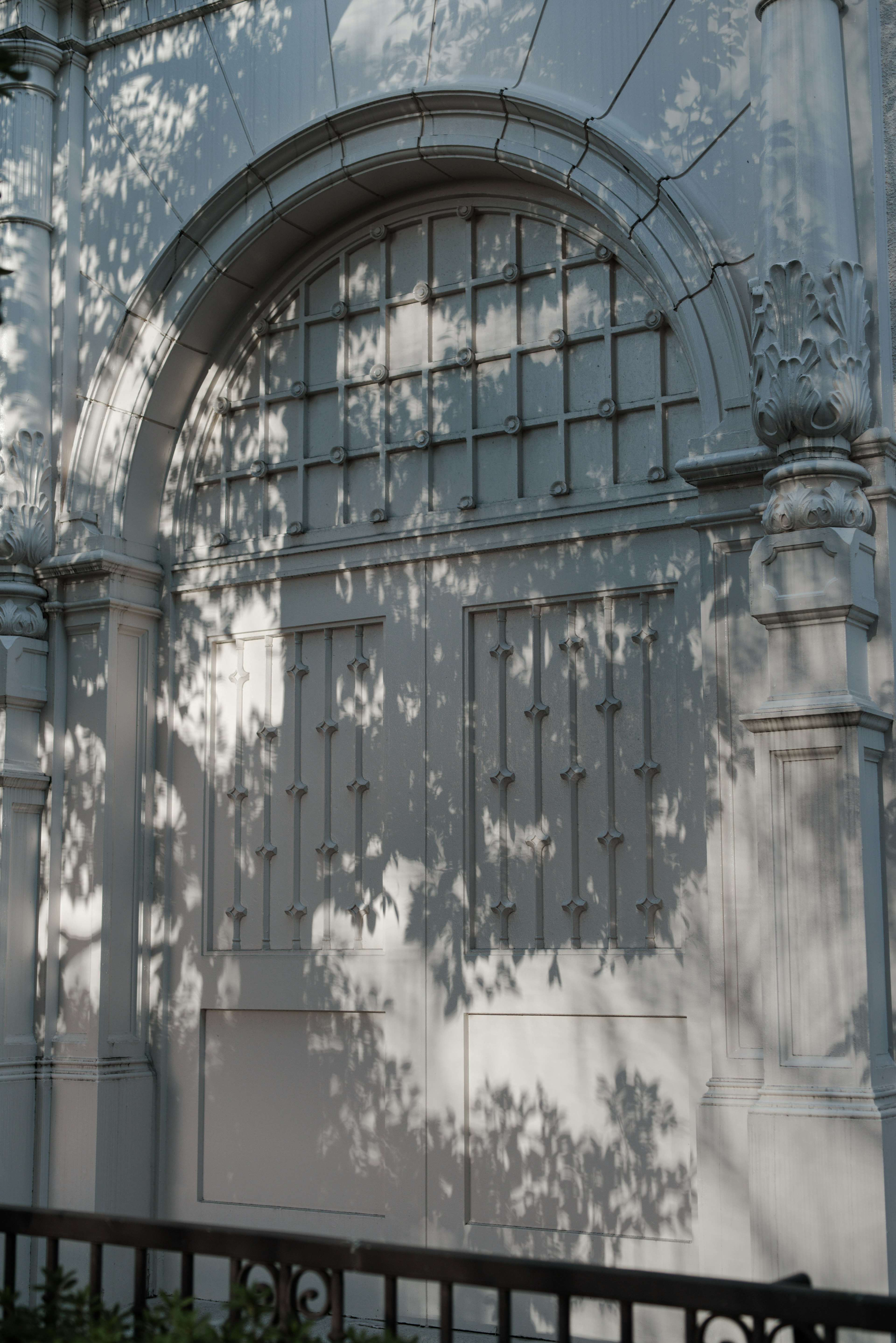 White wall with an arched window and shadow patterns