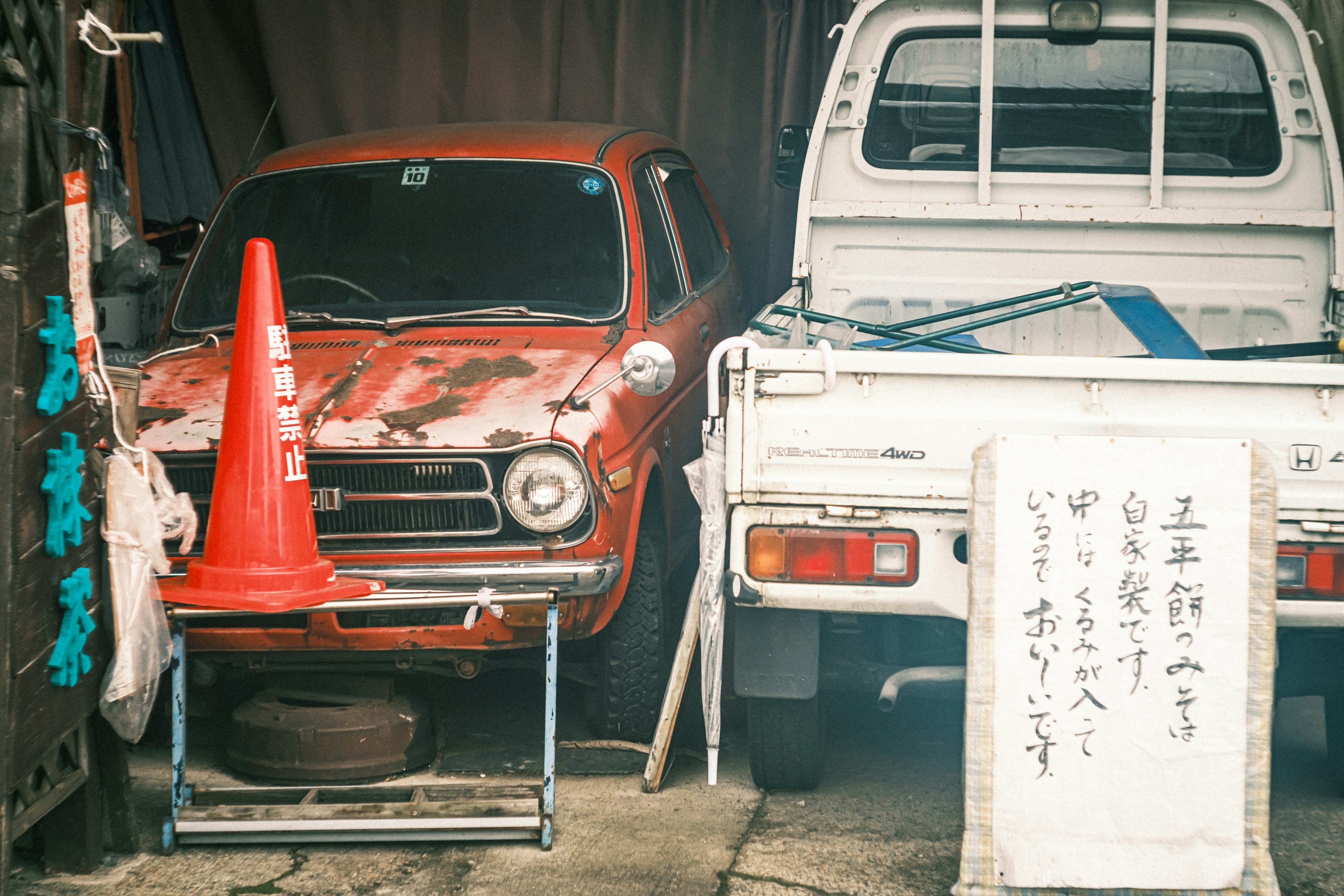 A classic red car and a white truck parked side by side in a garage