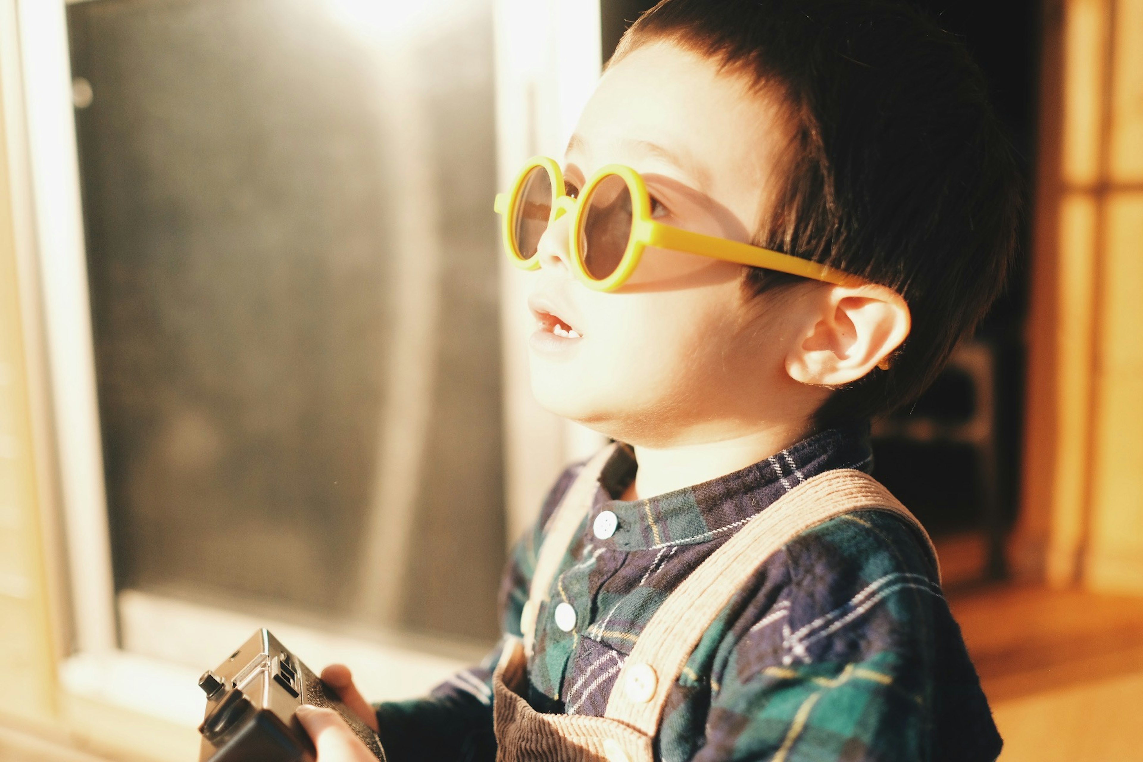 Un niño con gafas de sol amarillas sostiene una cámara