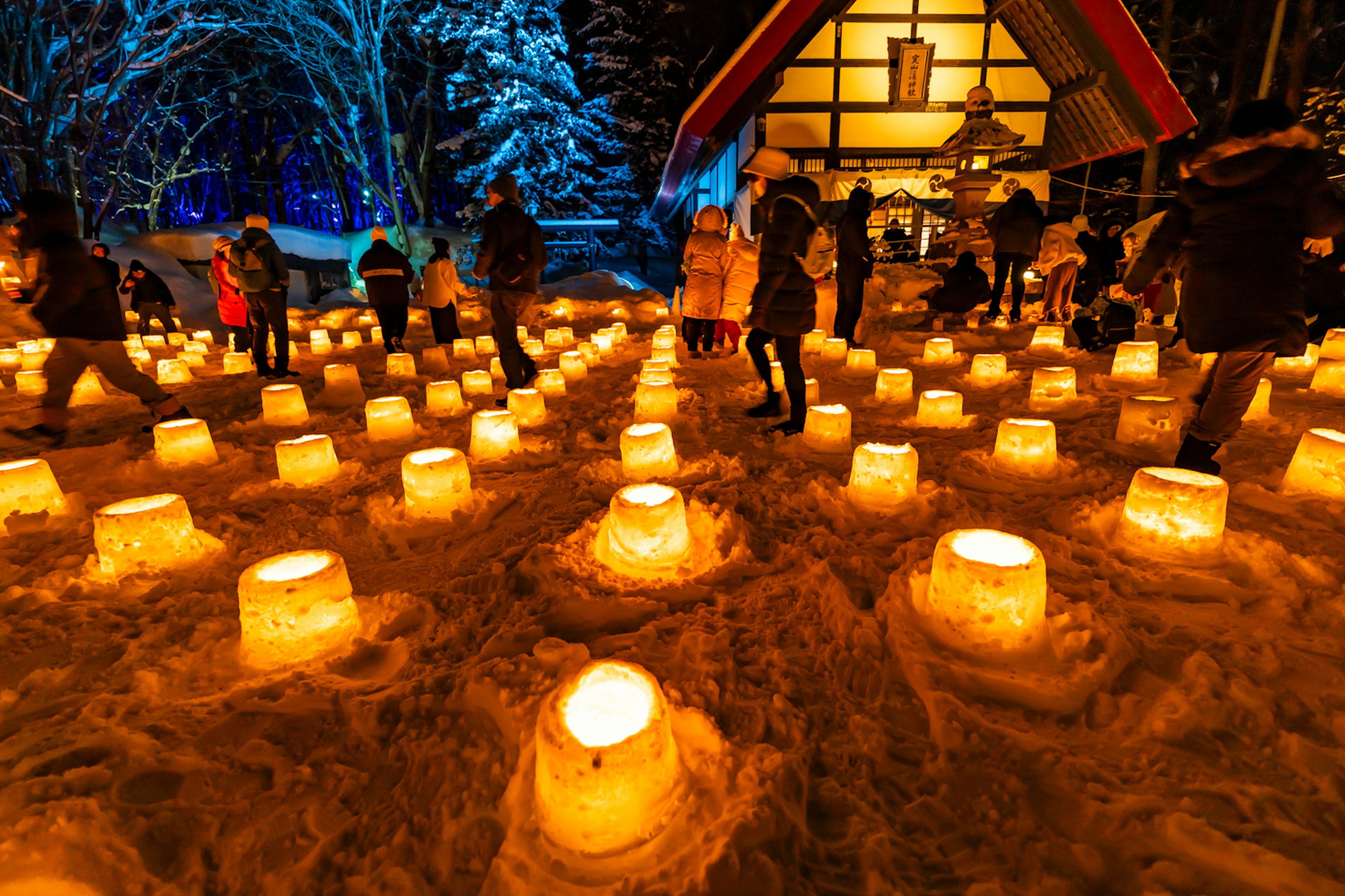 Bright lights glowing on a snowy landscape with people walking