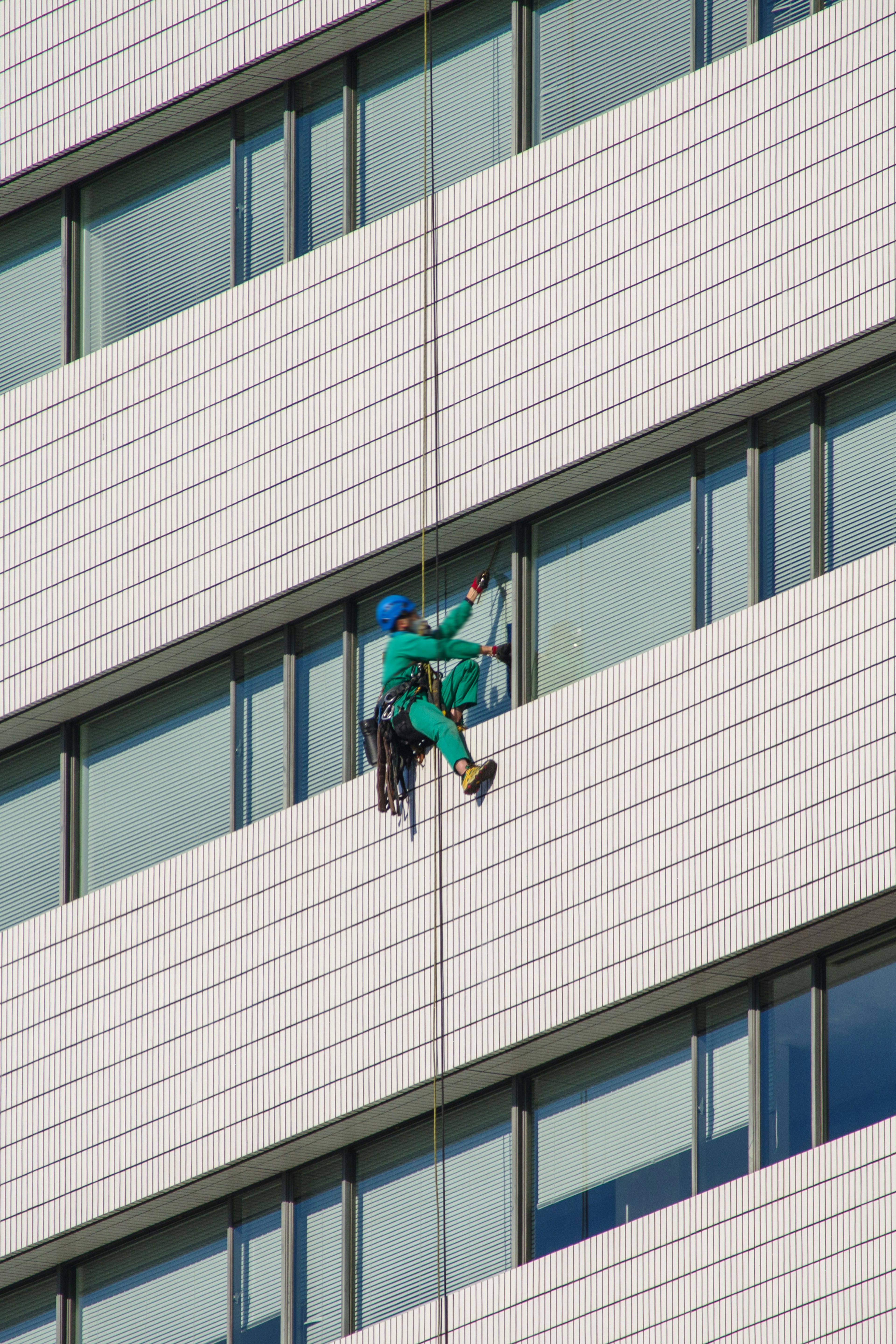 Arbeiter reinigt die Fassade eines Gebäudes und steigt an einem Seil ab