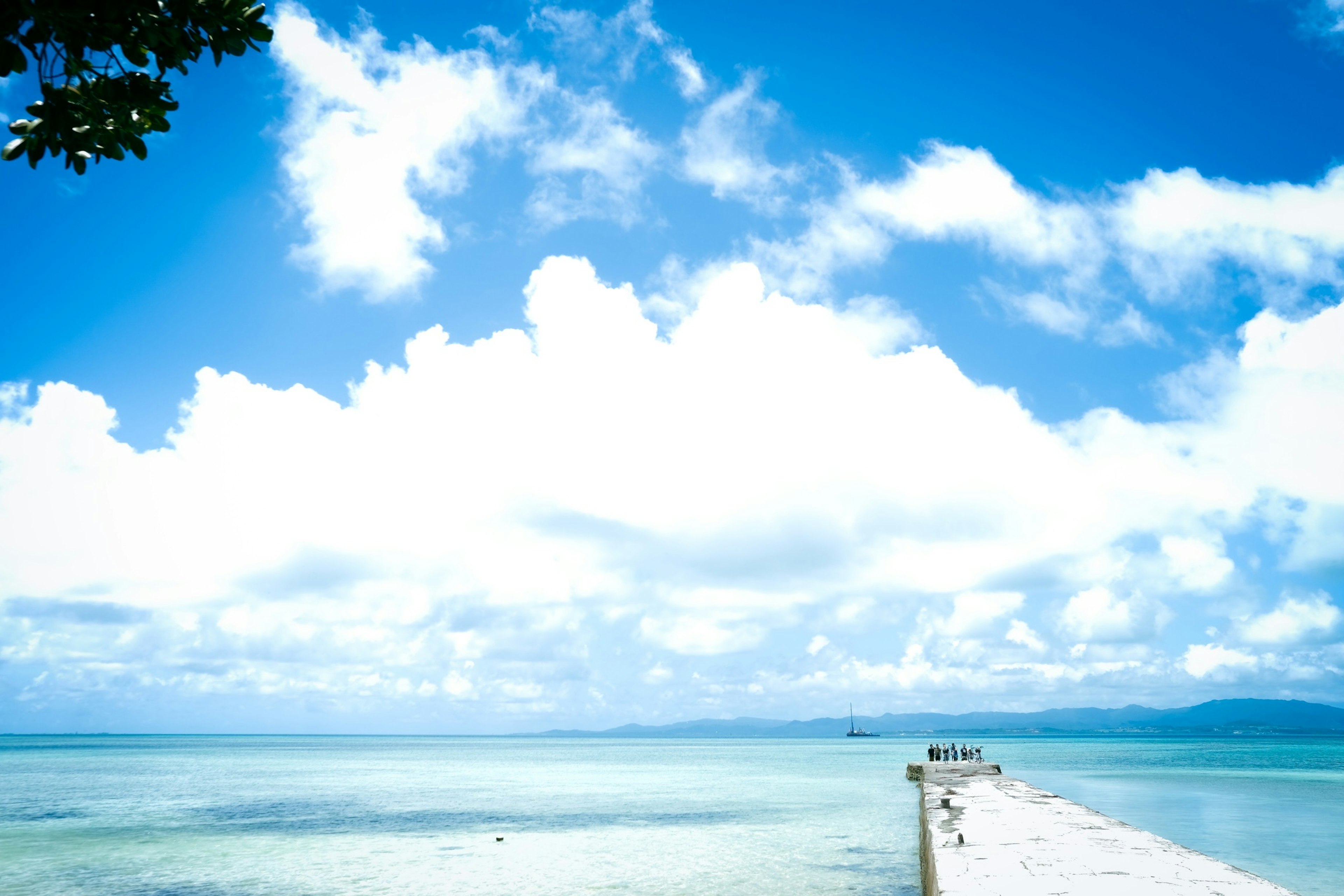 Pemandangan pantai dengan langit biru dan awan dermaga yang membentang ke dalam air