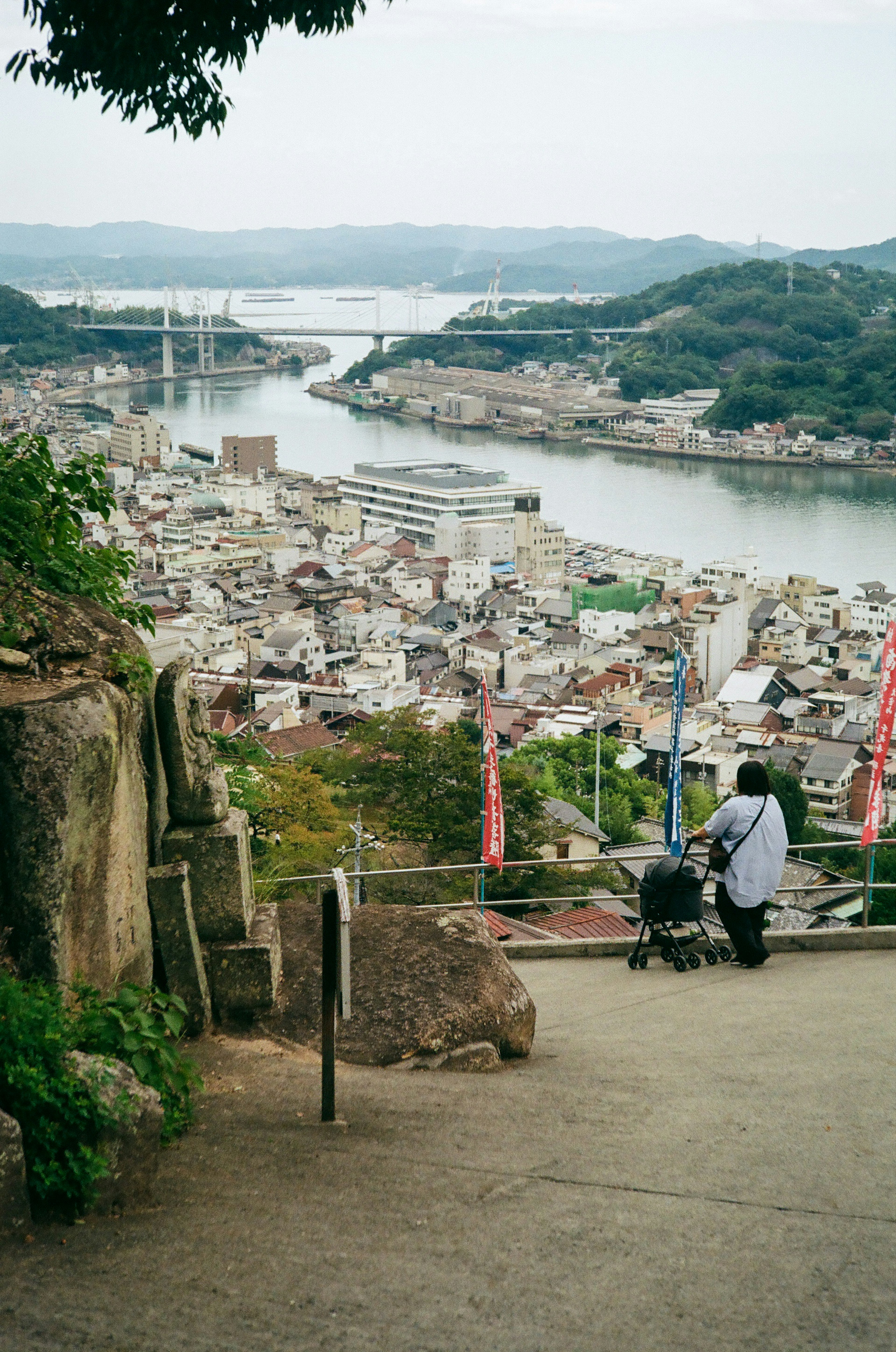 A scenic view of a river and town from a hill with two people sitting