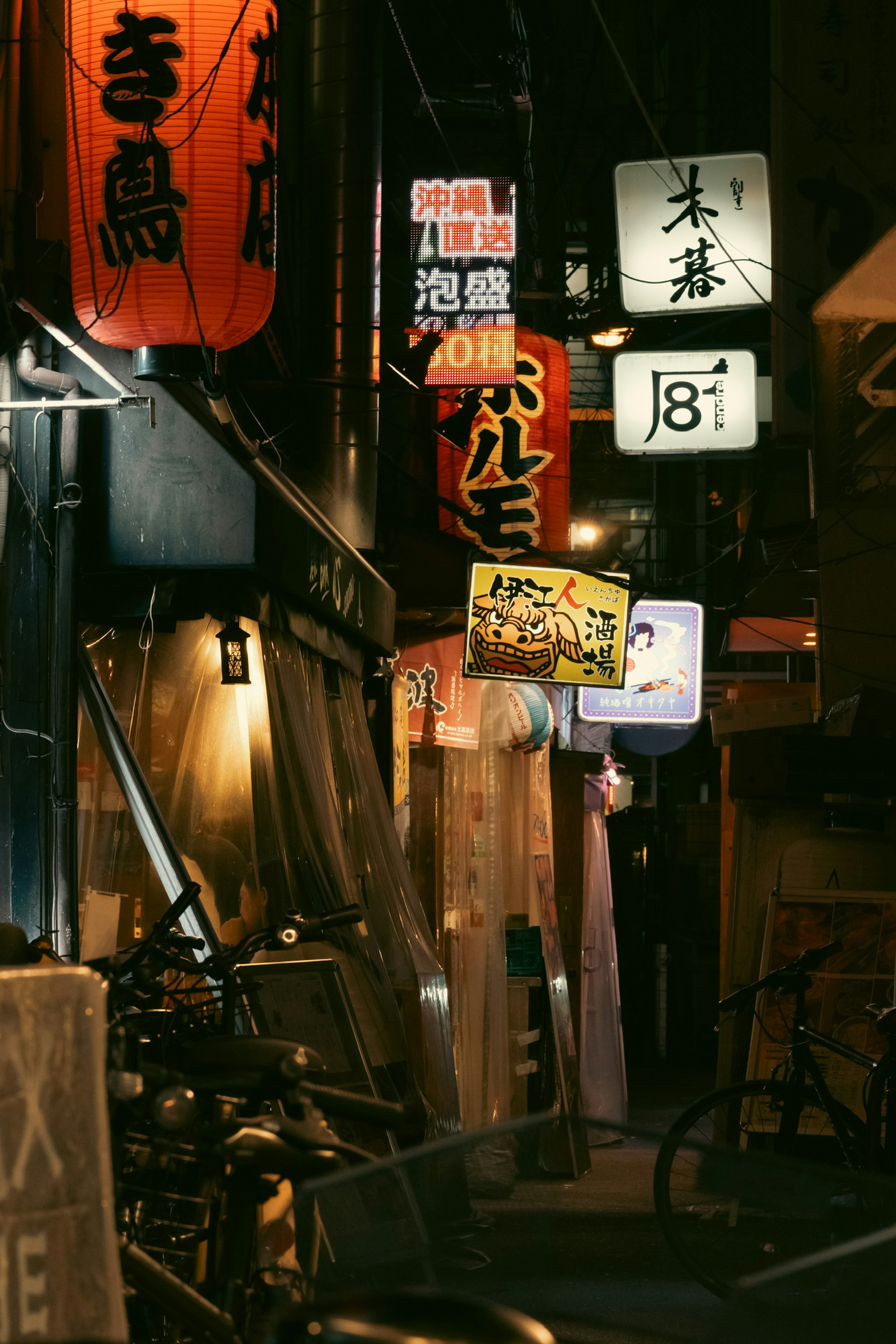 Narrow alley lined with neon signs and bicycles