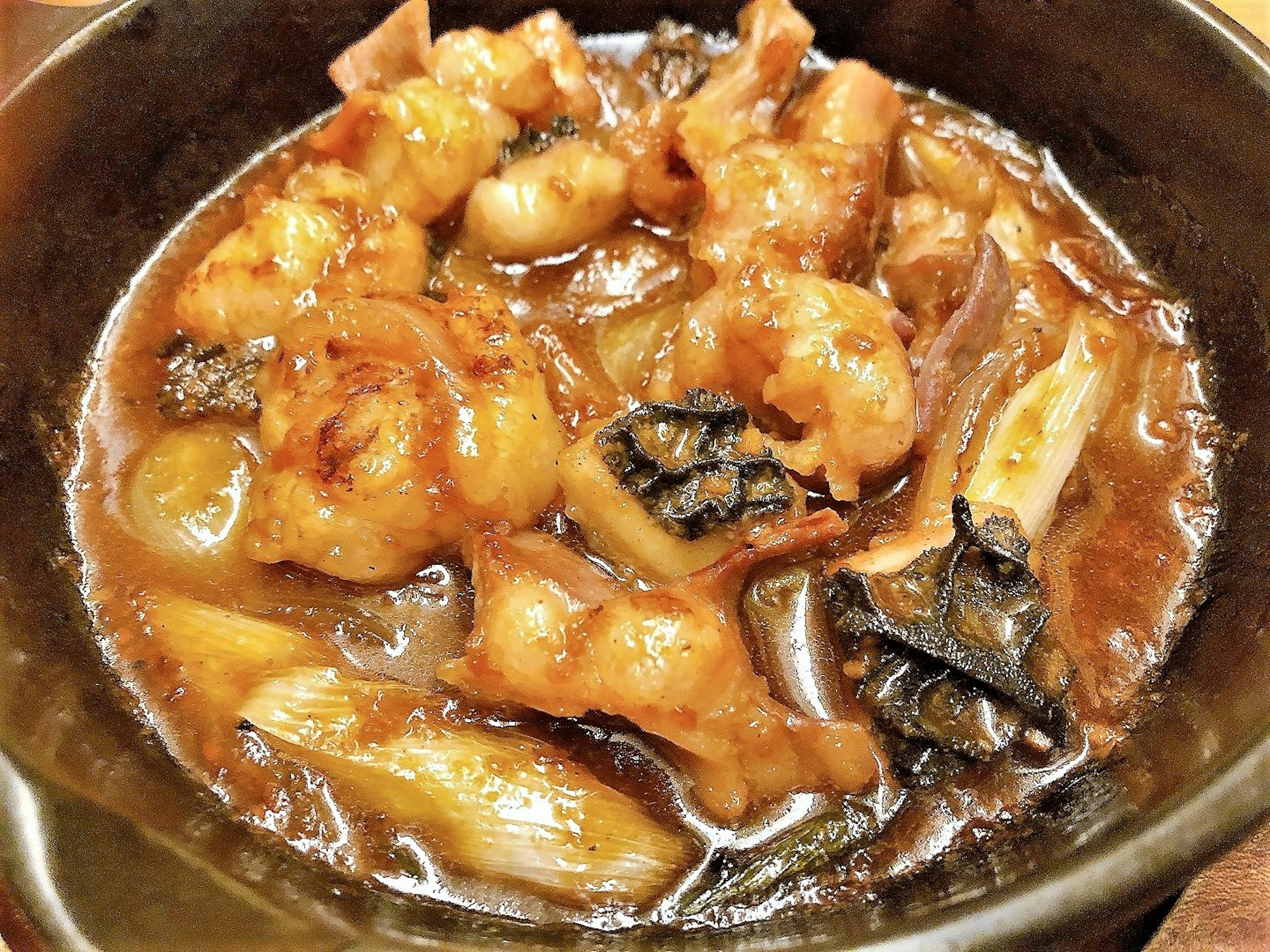 Braised meat and vegetables served in a black bowl