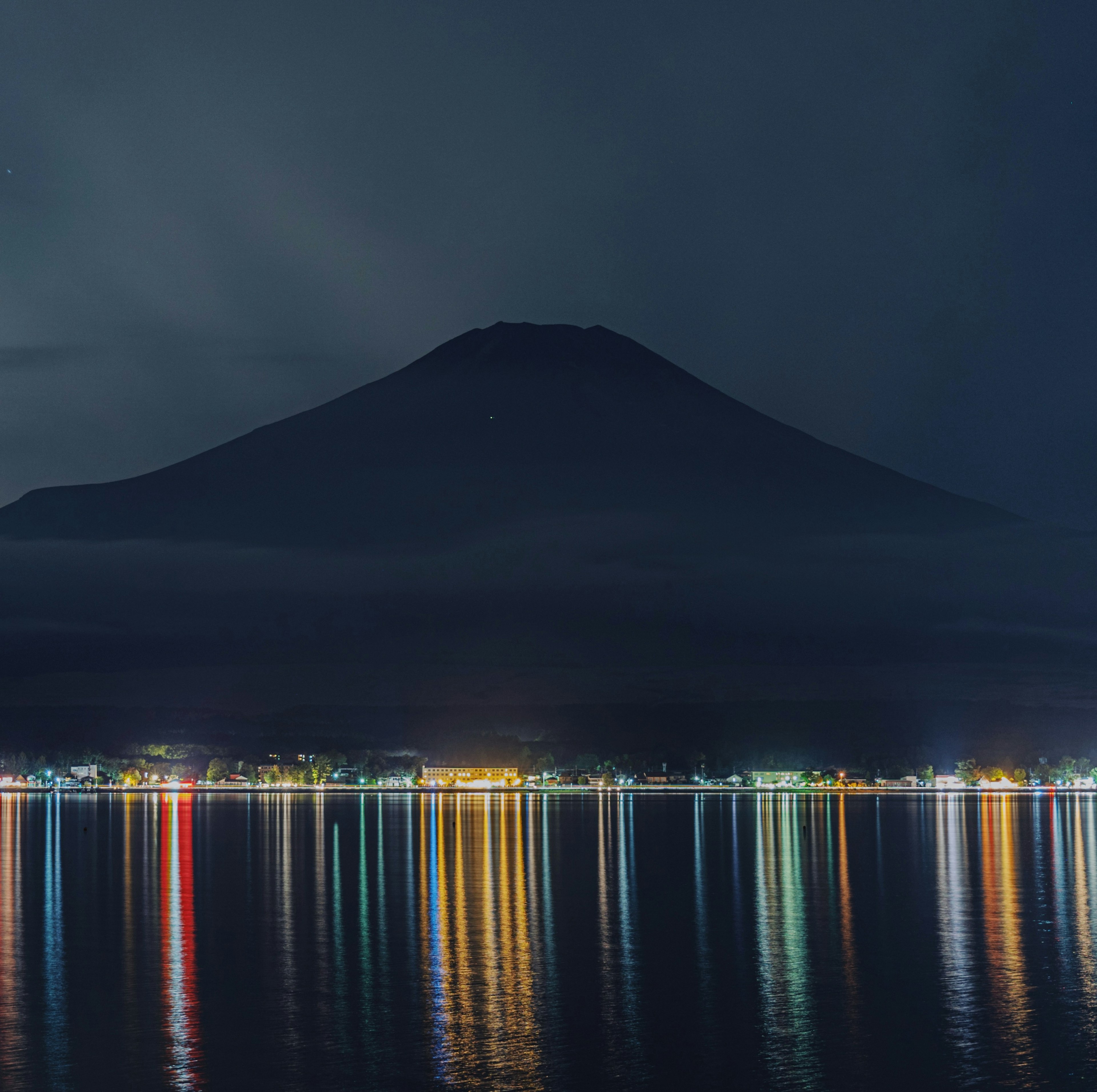 Mont Fuji la nuit avec des reflets colorés sur l'eau